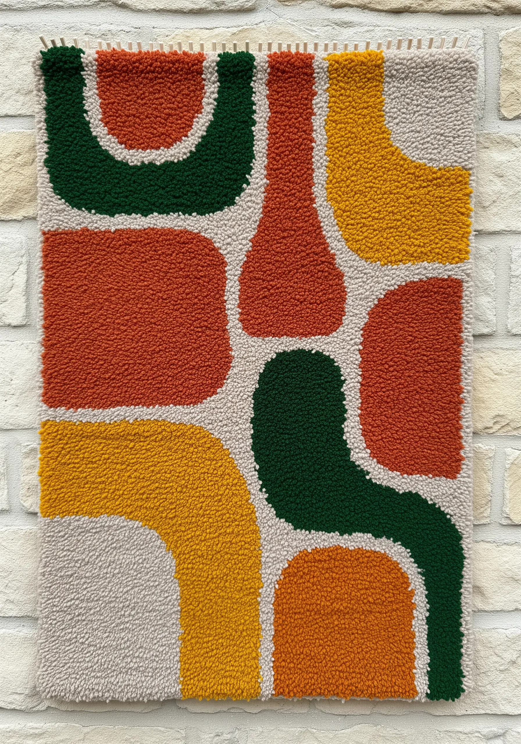 Punch needle wall hanging with abstract, rounded shapes in rust, green, yellow, and beige.