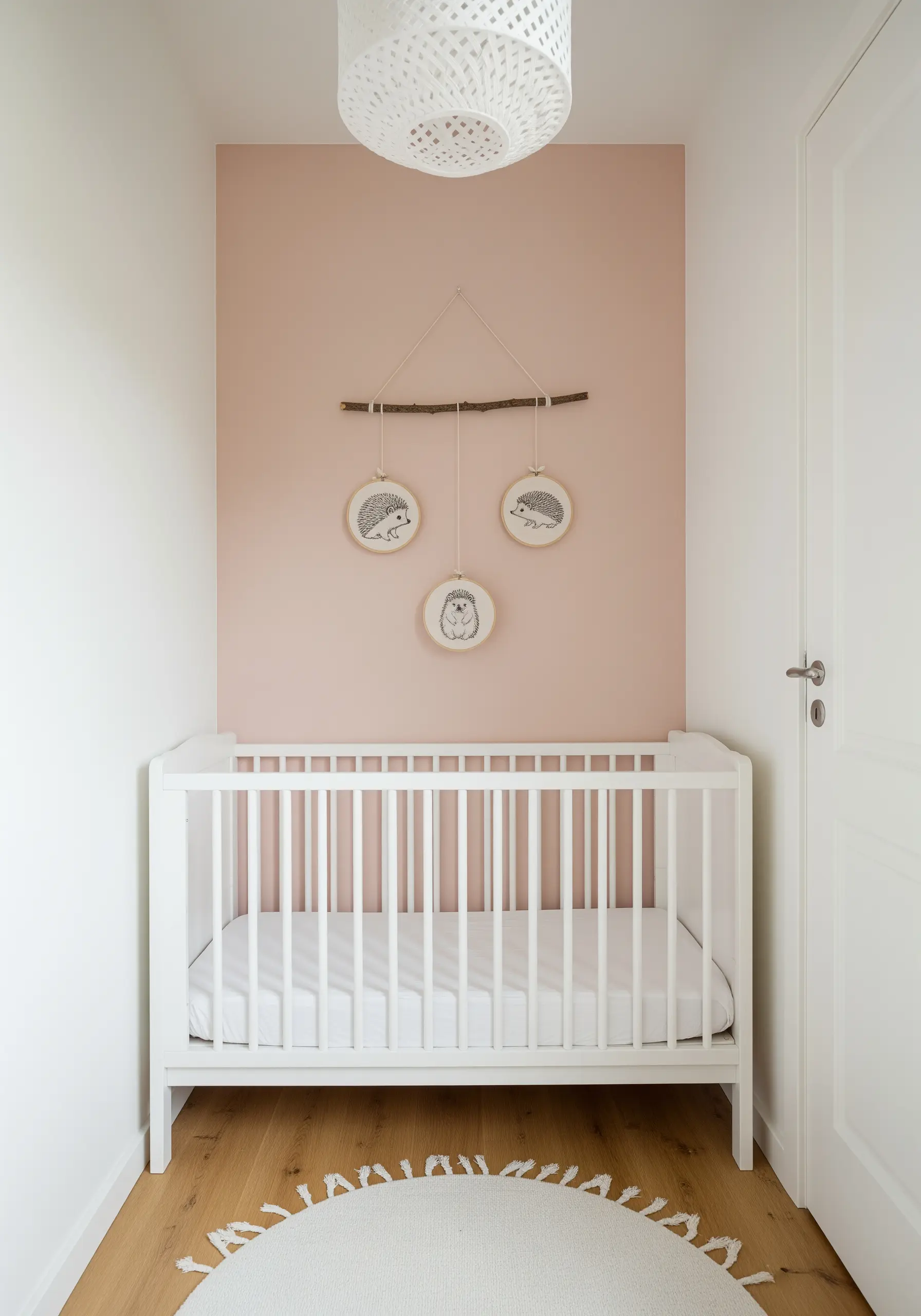 Three small embroidery hoops featuring hedgehogs, hanging from a natural wooden branch above a white crib.