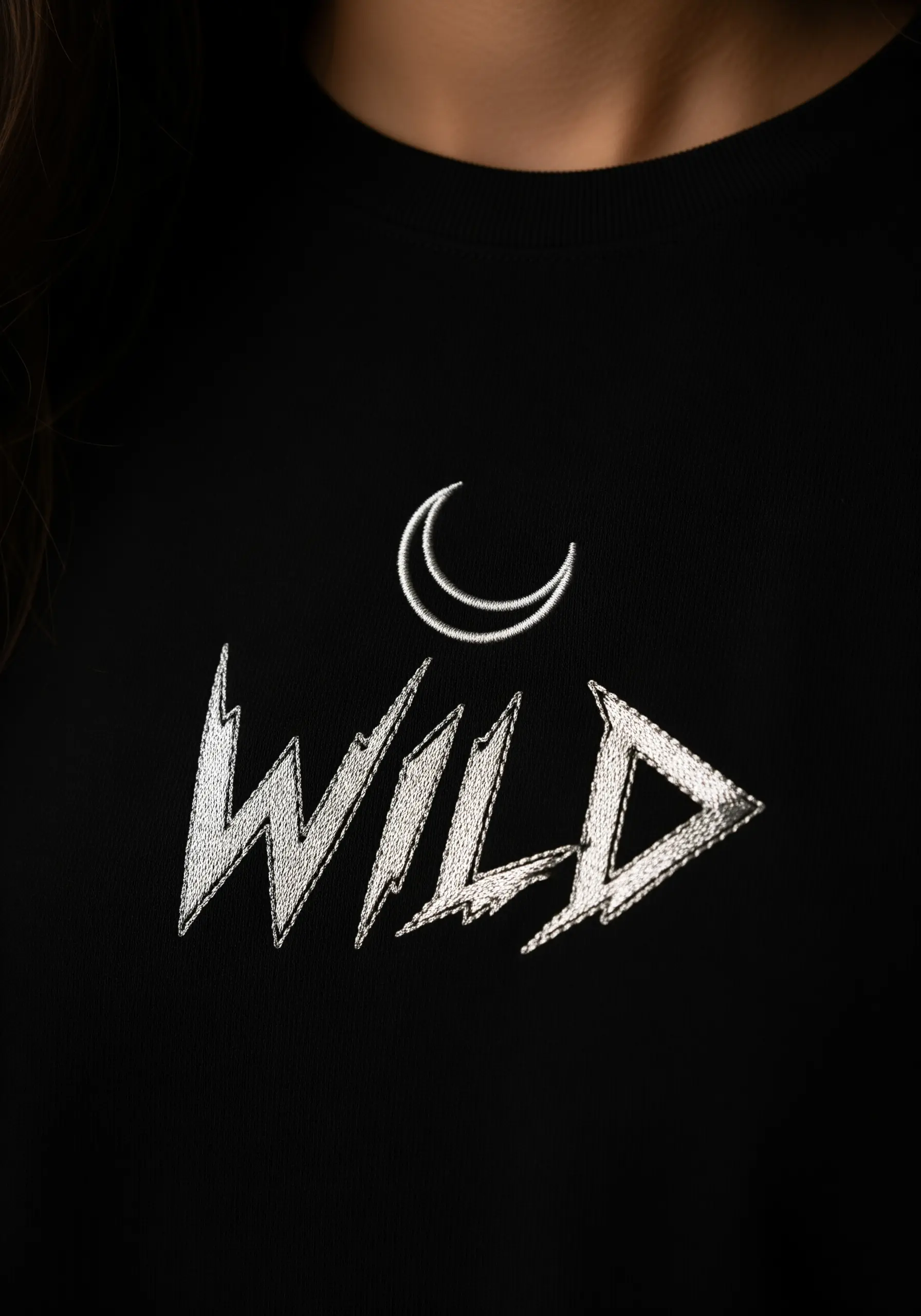 The word 'wild' embroidered in a jagged, textural font with a crescent moon above it