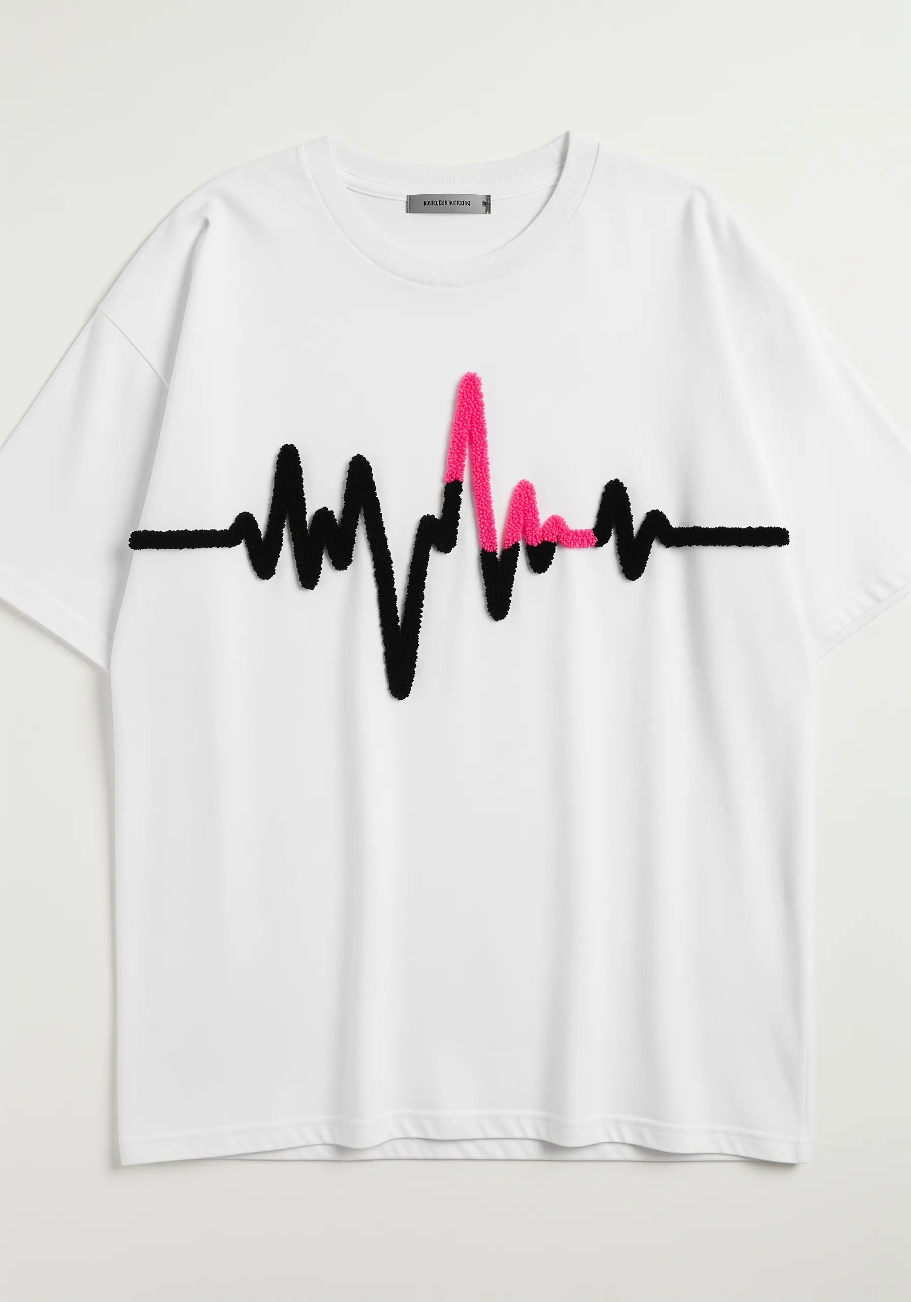 A heartbeat (EKG) line embroidered in a fuzzy, high-pile stitch in black and pink.