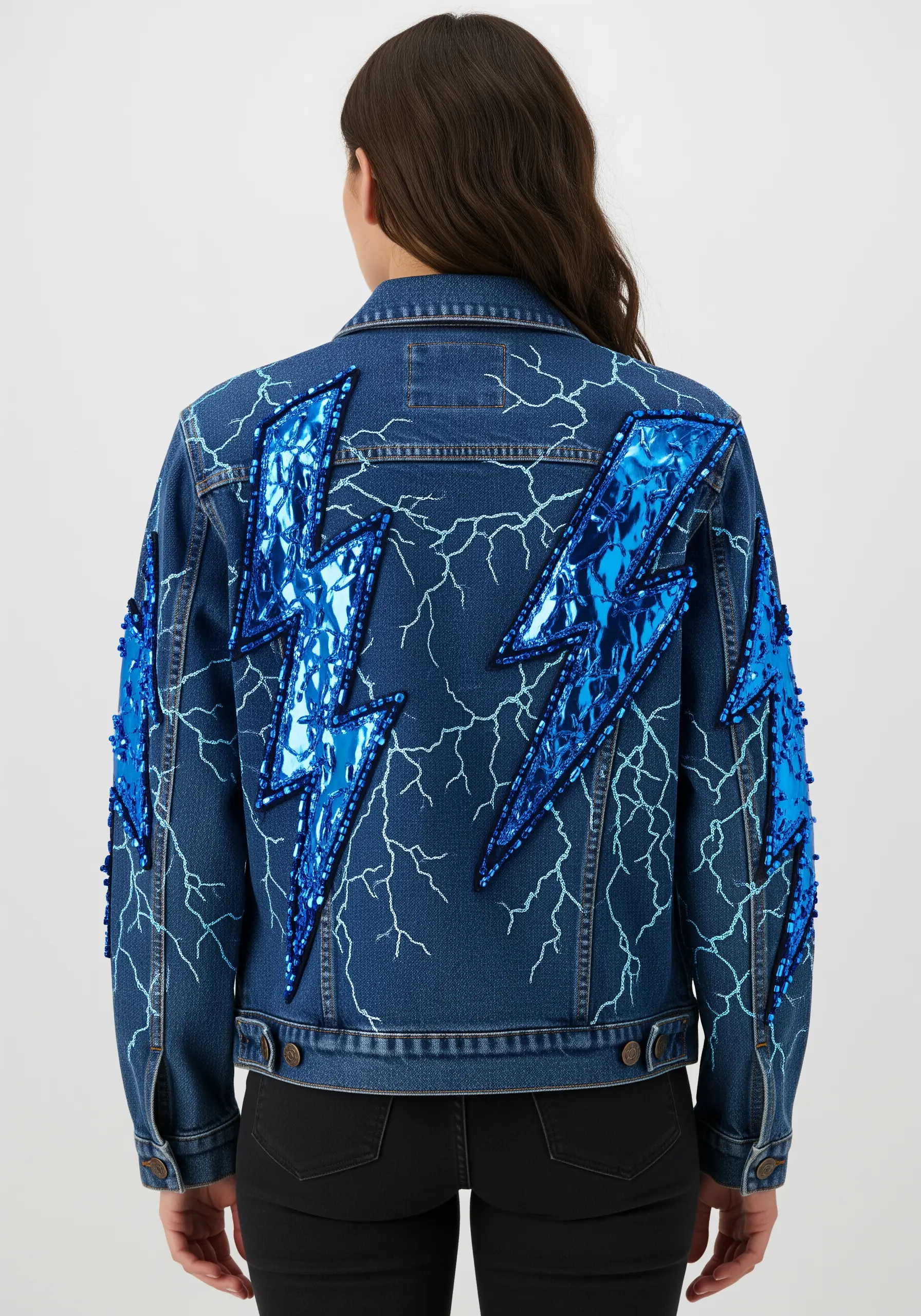 Denim jacket with large metallic blue lightning bolt appliqués and stitched details.