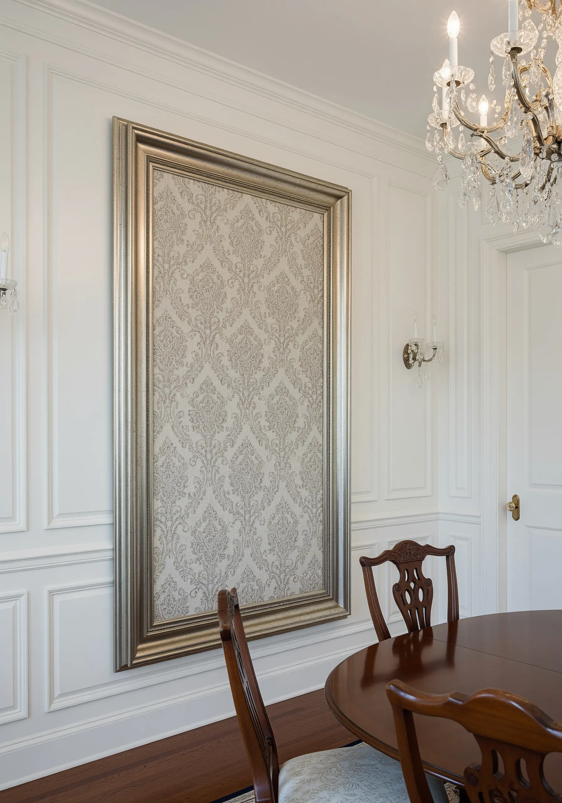 A large piece of silver and cream damask fabric stretched and mounted in an ornate silver frame.