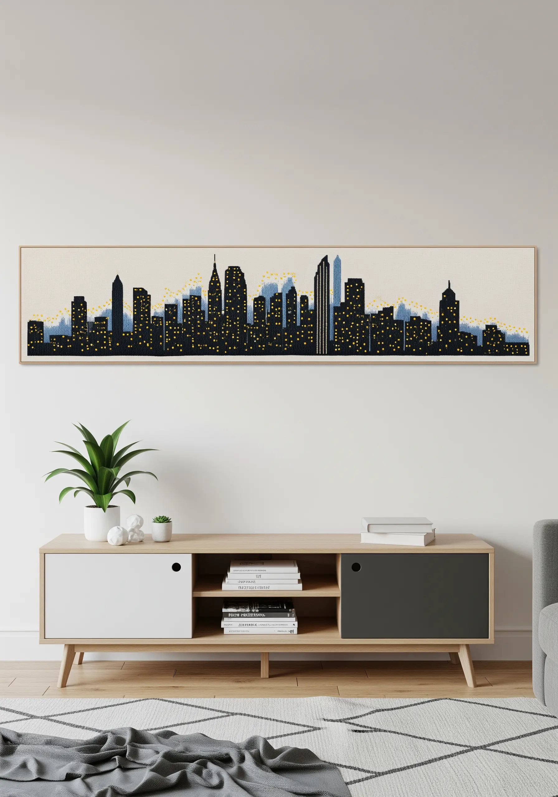 A long, panoramic framed embroidery of a city skyline at night with yellow lights.
