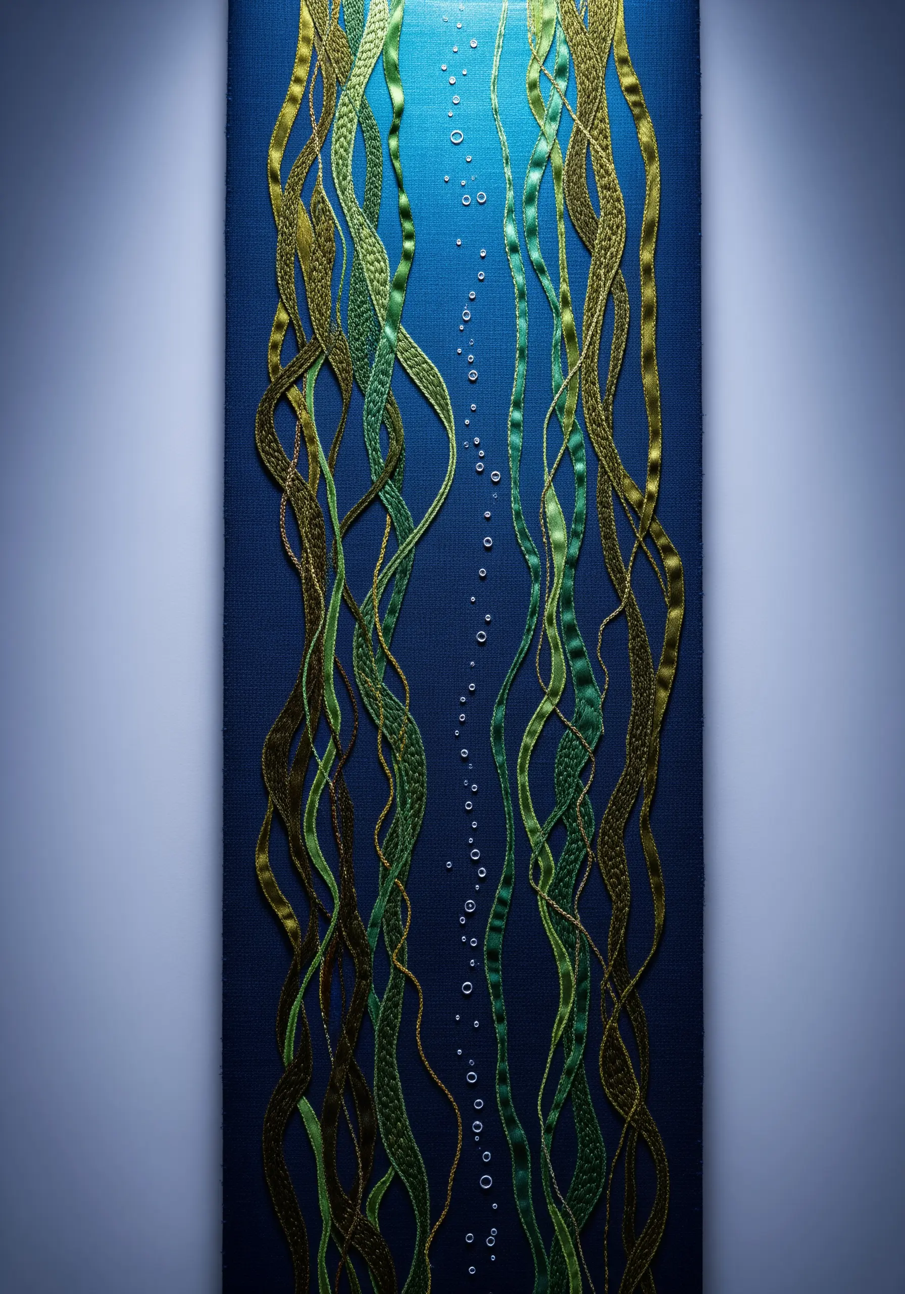 Embroidered wall art of flowing green seaweed ribbons against a deep blue background.