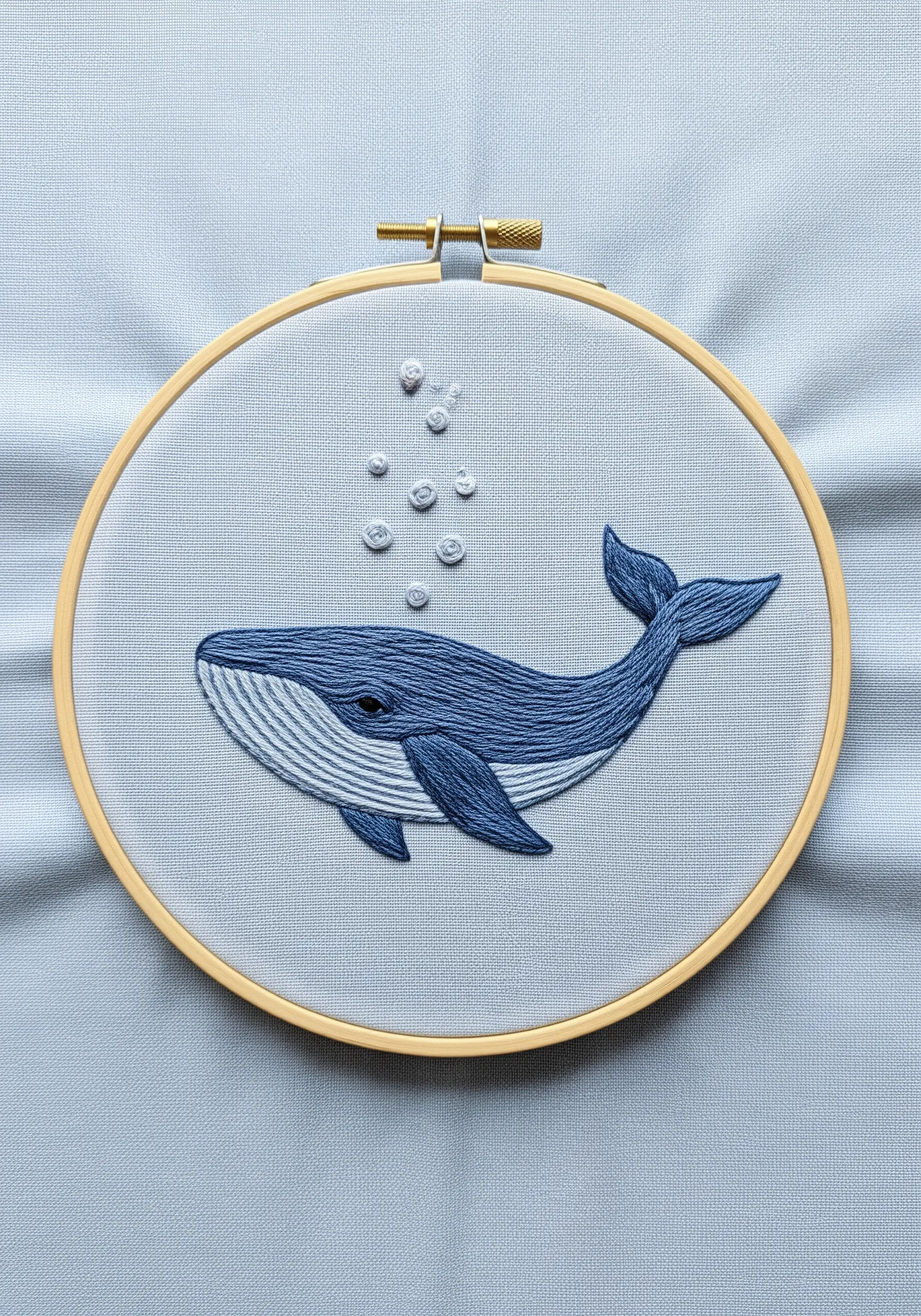 A blue whale embroidered with long-and-short stitch gradients on light blue fabric.