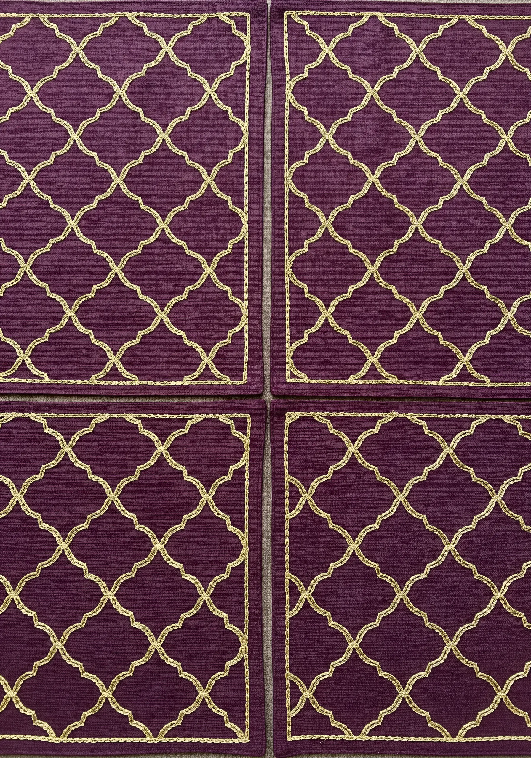 Purple placemats with an all-over Moroccan trellis pattern embroidered in gold metallic thread.