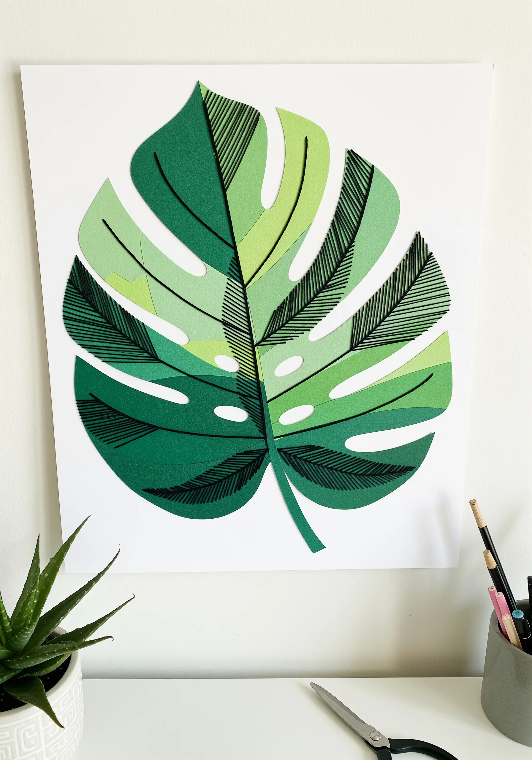 A paper collage monstera leaf with black straight stitches creating vein textures.