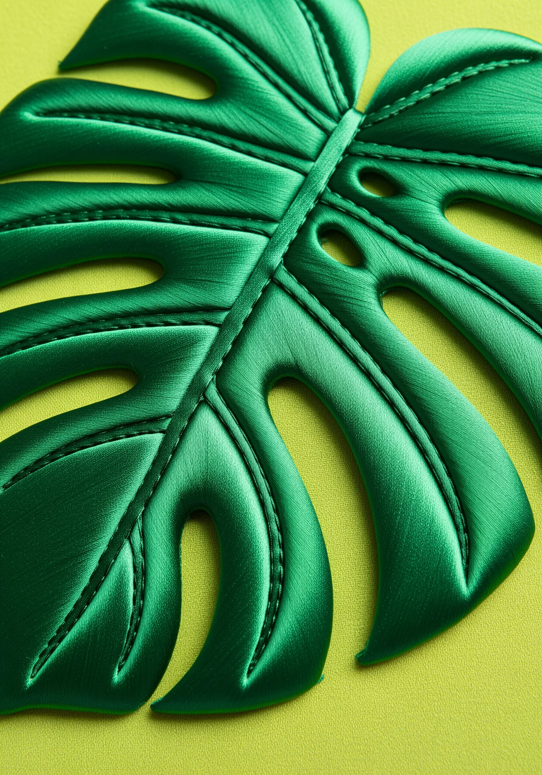 Machine-stitched veins on a sleek, green faux leather monstera leaf.