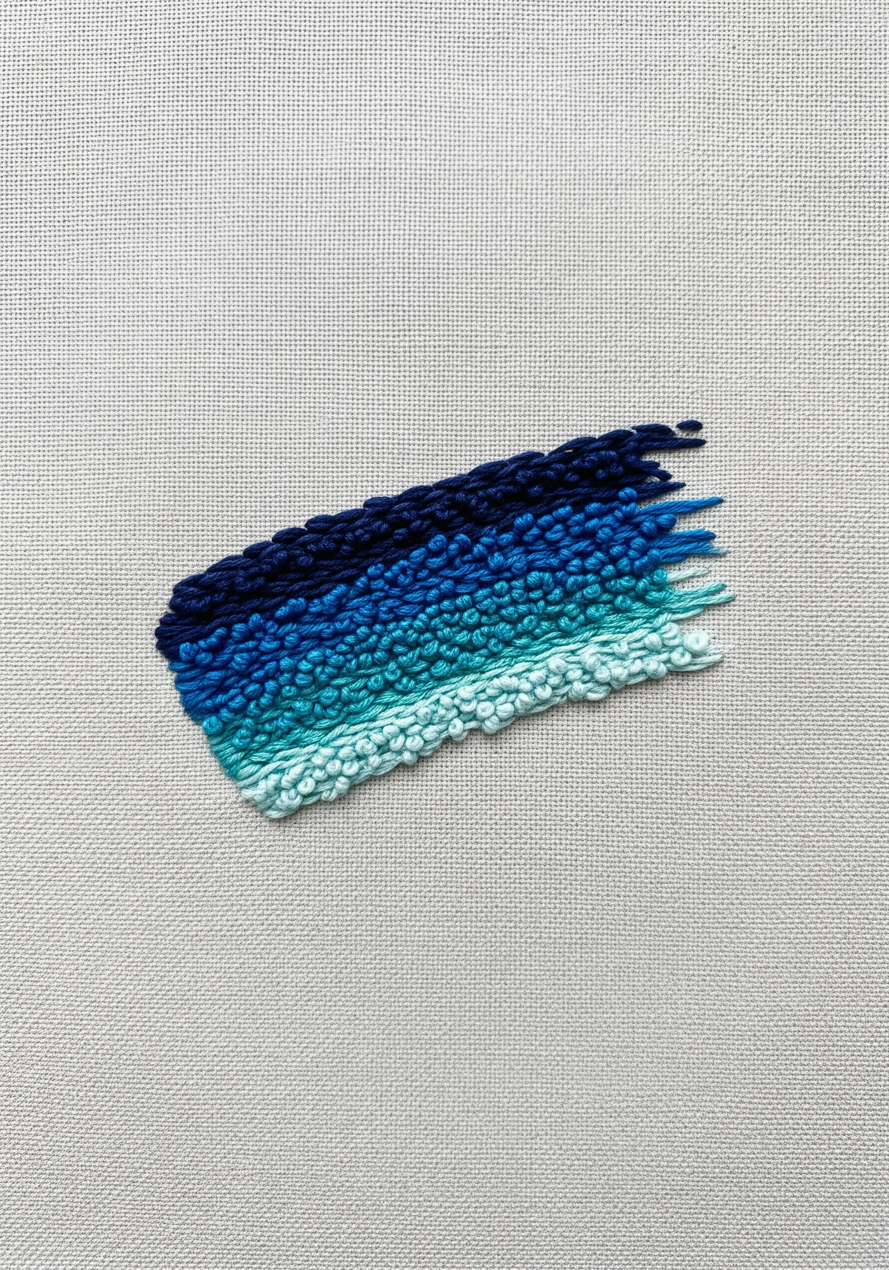 An abstract gradient of blue tones created with dense French knot clusters.