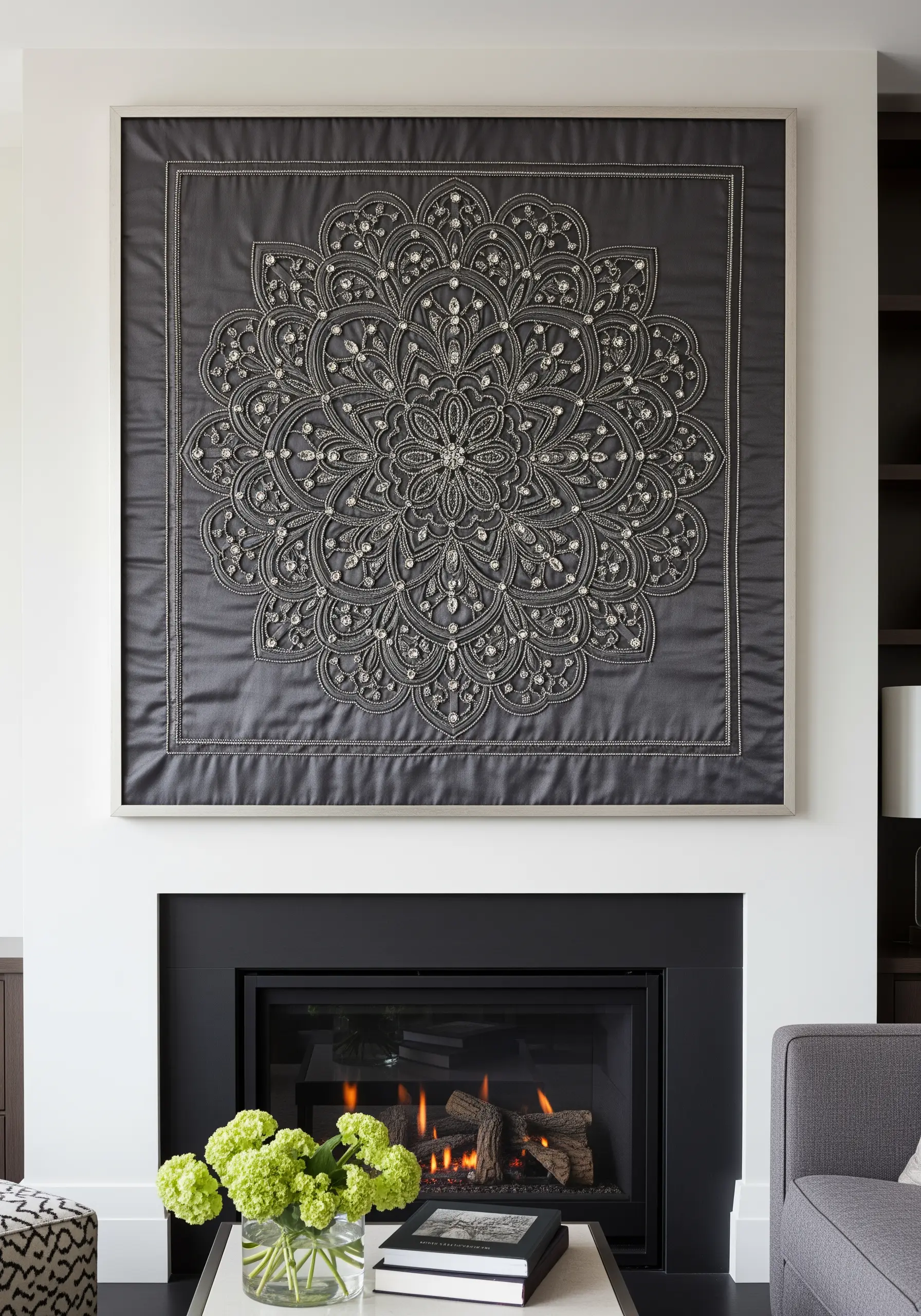 A large, intricately embroidered and beaded gray mandala hanging above a fireplace.