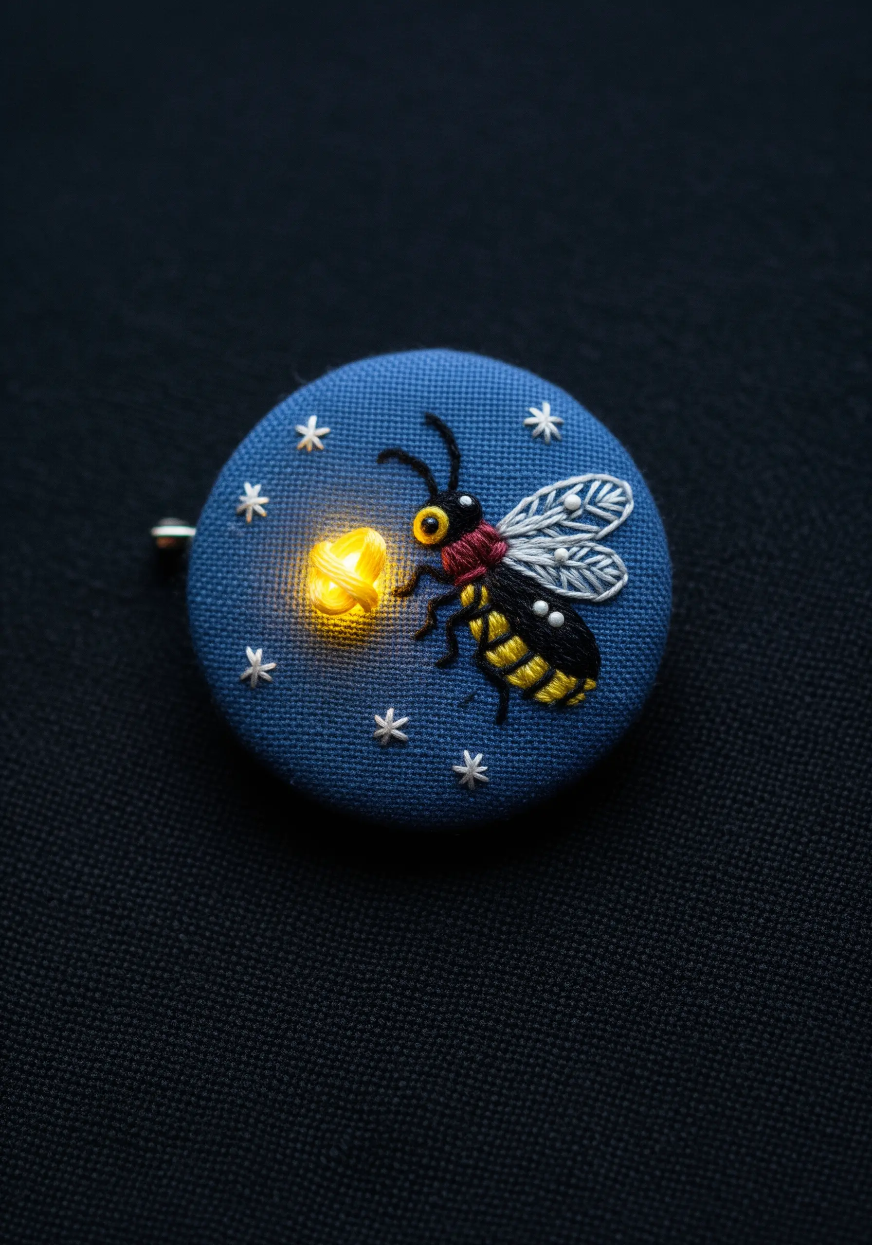 An embroidered firefly pin with a tiny light that makes its abdomen glow.