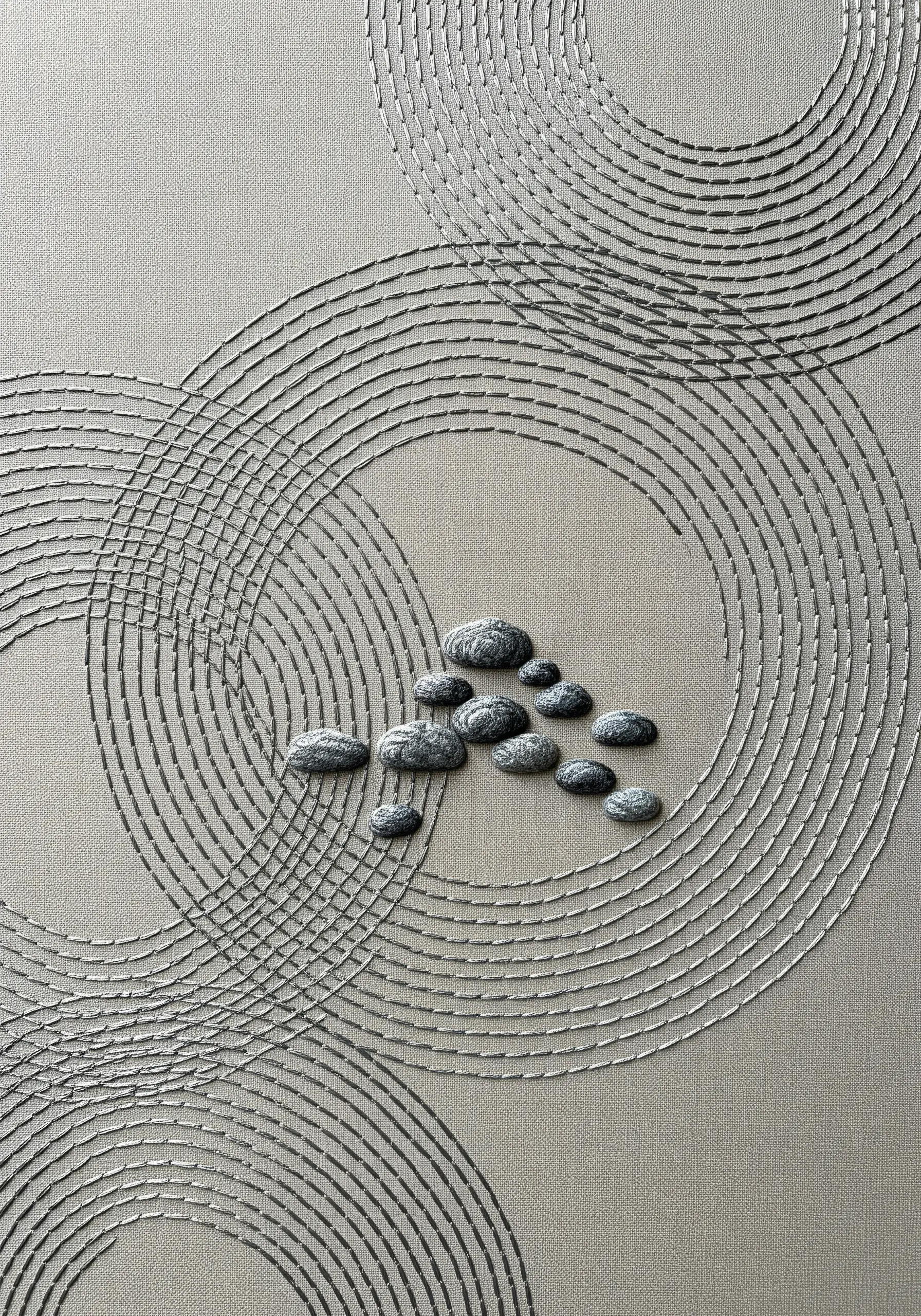 Minimalist art with beaded circles and padded satin stitch stones on neutral canvas.