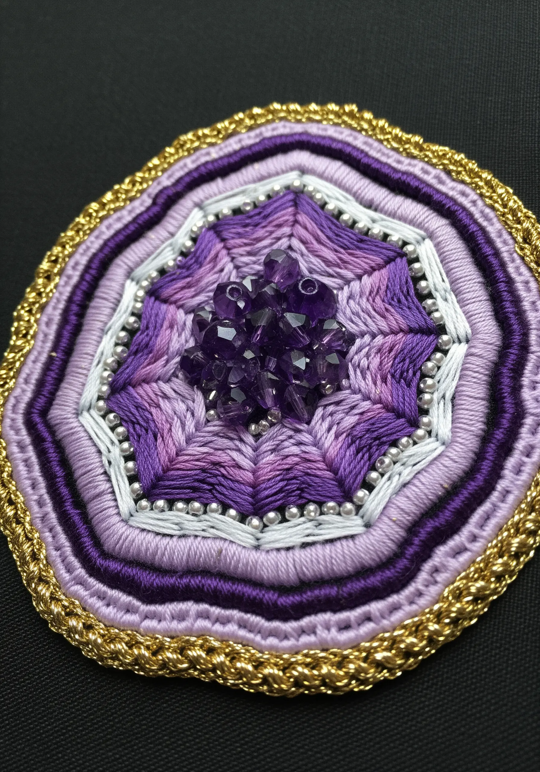 Purple geometric mandala with satin stitches, metallic thread, silver beads, and amethyst crystals.