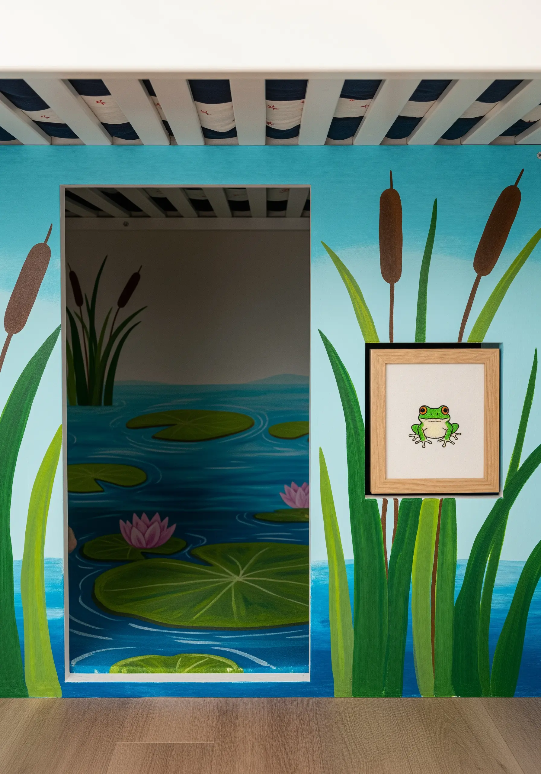 A small, framed embroidery of a frog placed on a wall painted with a pond and lily pads scene.