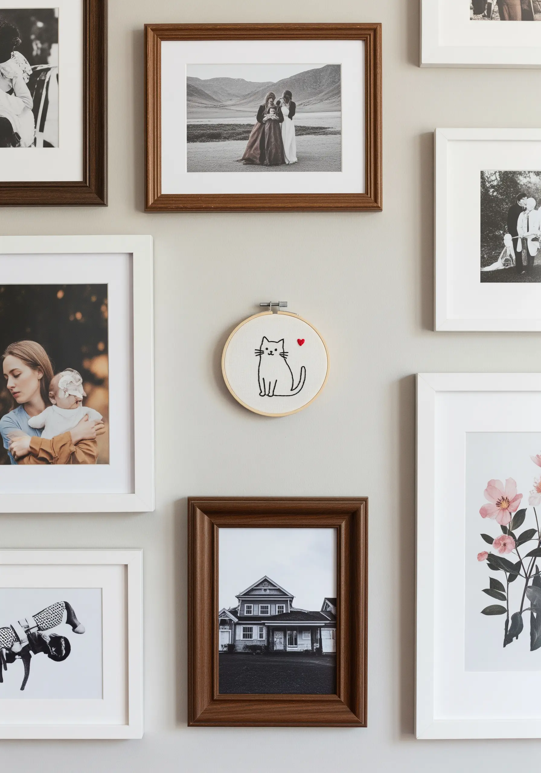 A small hoop with a line-art cat embroidery hanging on a gallery wall.