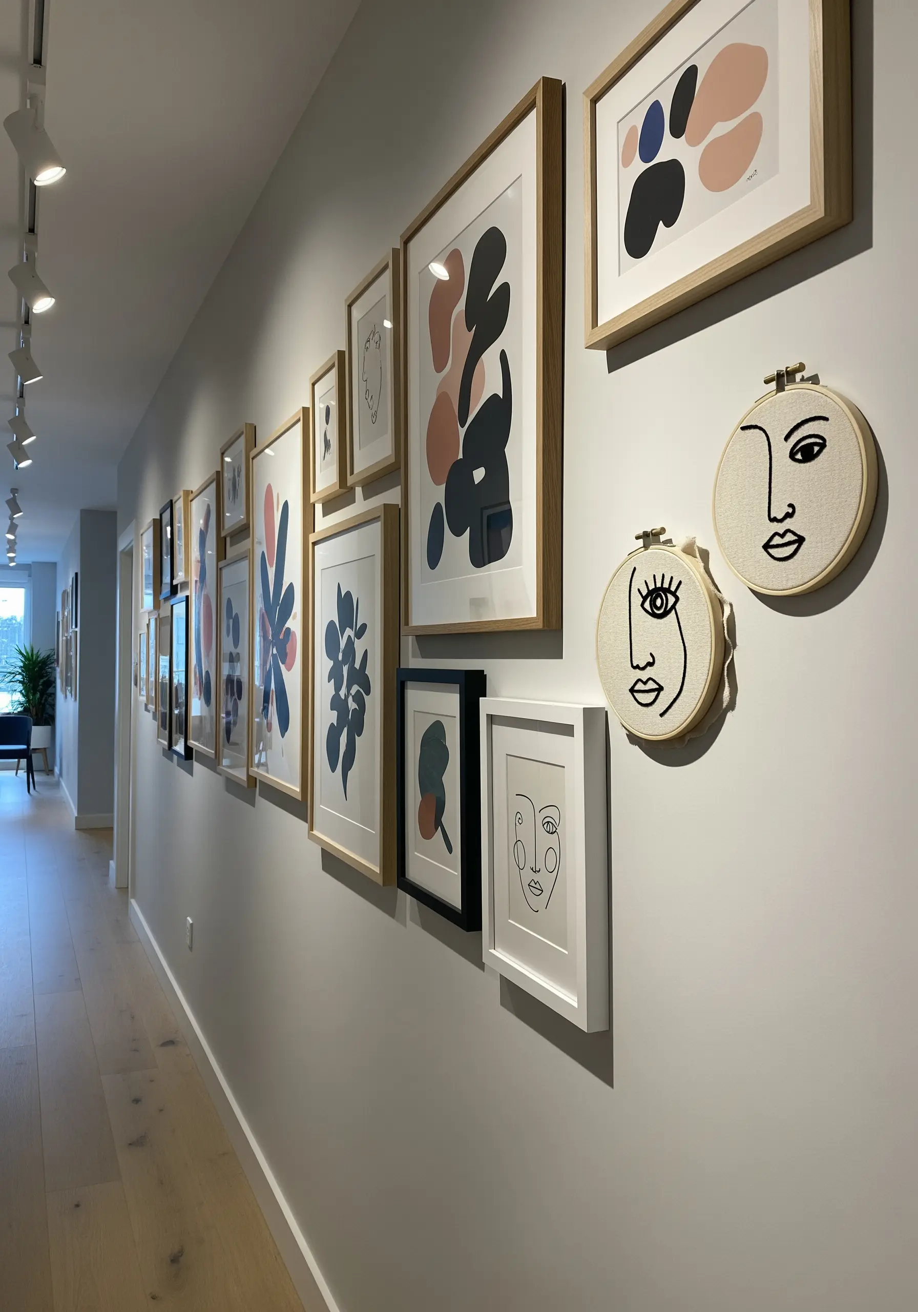 Two small embroidery hoops with abstract faces integrated into a large gallery wall.