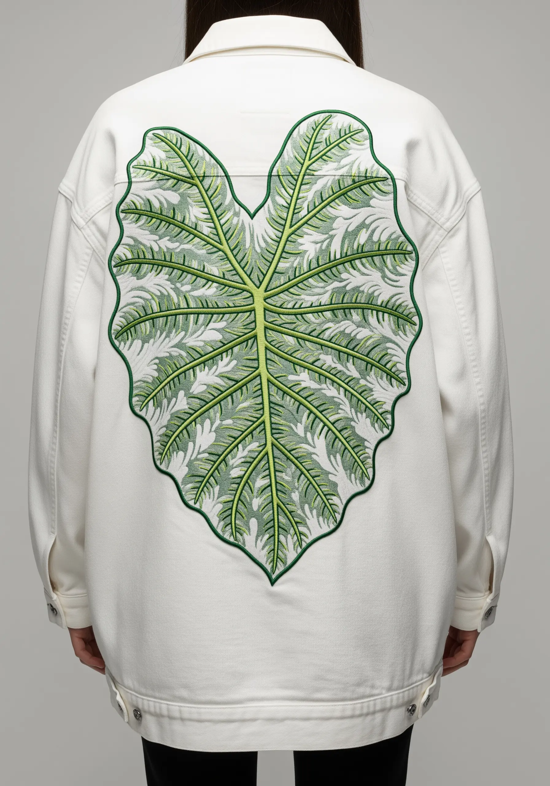 A large, intricately veined alocasia leaf embroidered on a white jacket.