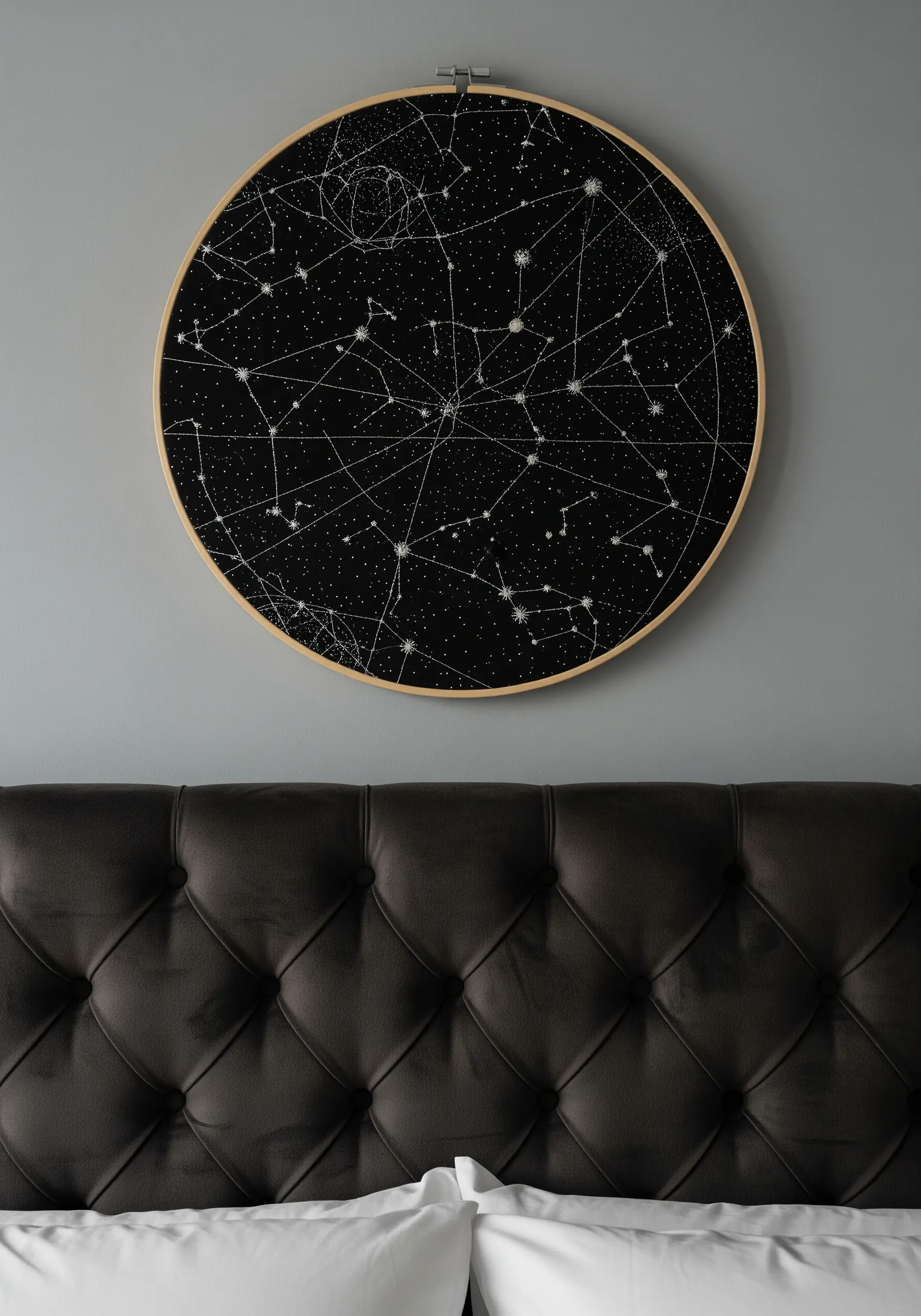 A large embroidery hoop with a detailed constellation map stitched in white on black fabric.