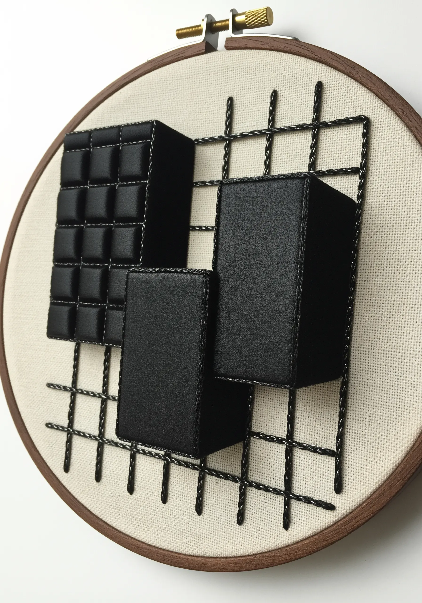 3D stumpwork embroidery with black padded cubes arranged on a stitched grid within a hoop.