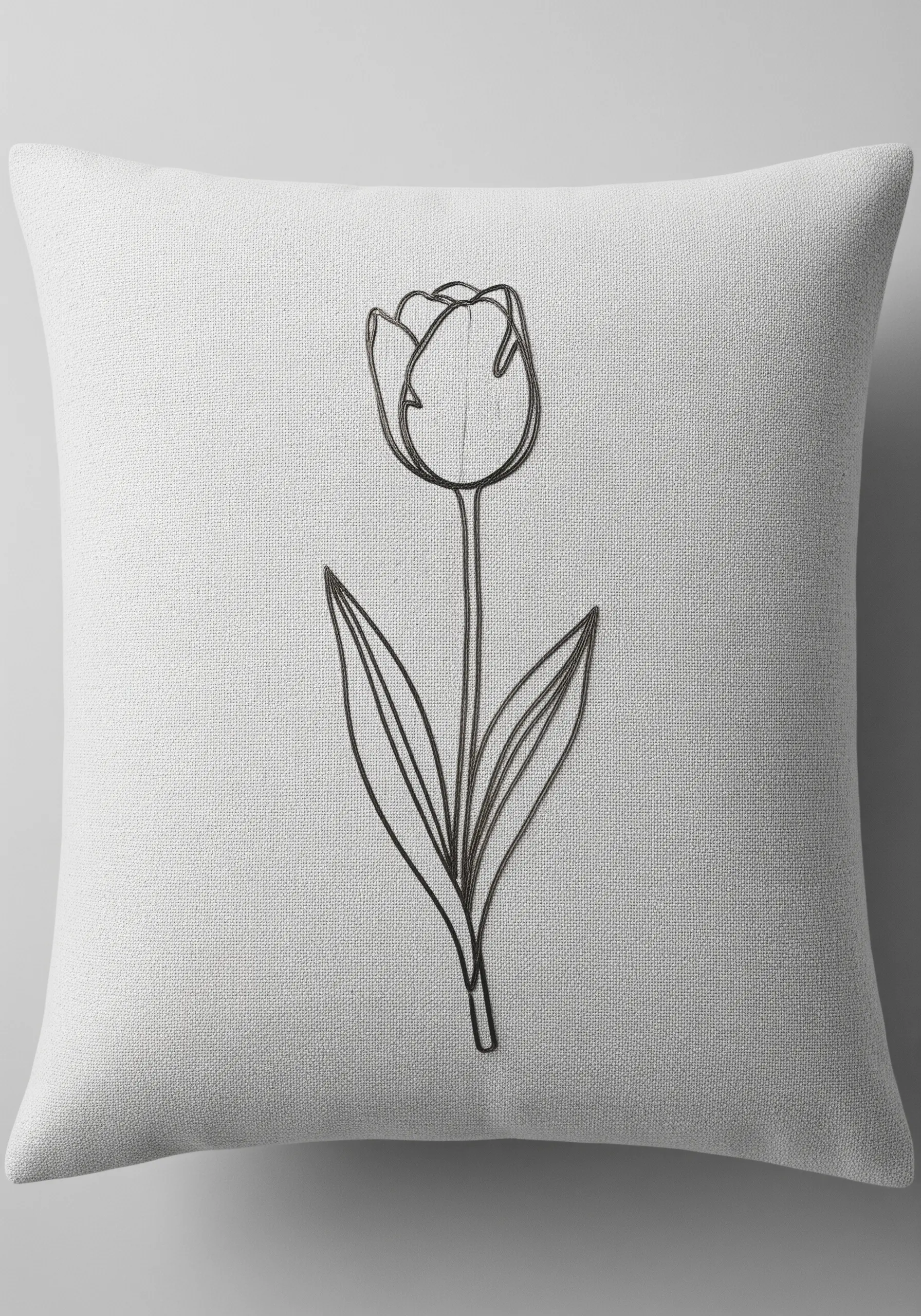 Minimalist tulip flower embroidered with a raised, 3D effect on a light grey cushion.