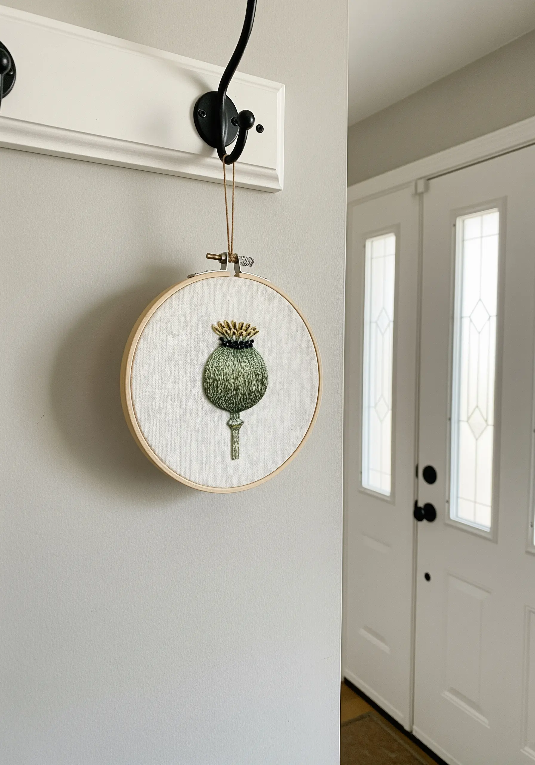 A single green poppy seed pod embroidered with 3D texture in a small hoop.