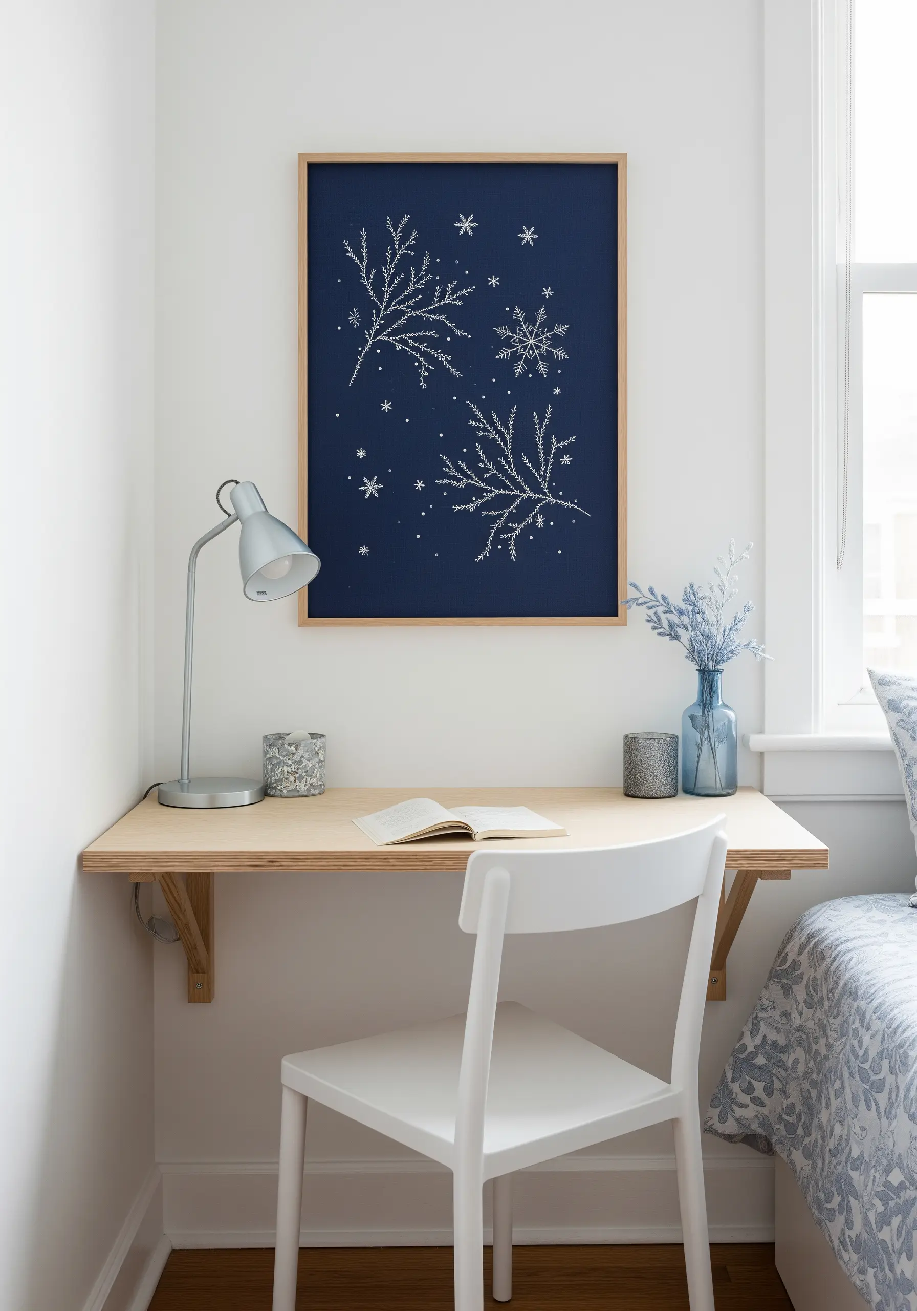 Framed embroidery of white frosty branches and snowflakes on a dark blue background.