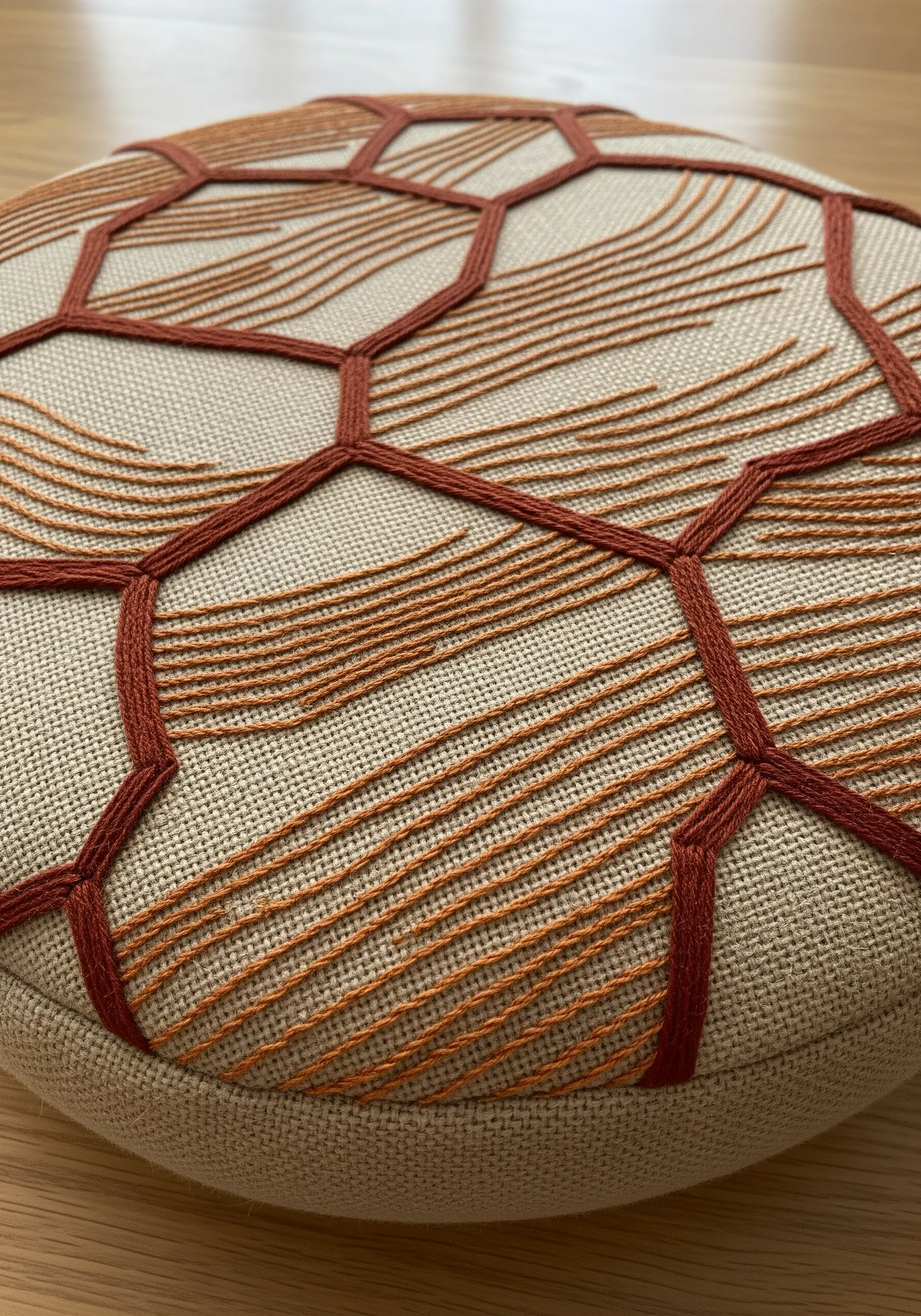 Close-up of a cushion with an embroidered honeycomb pattern filled with wavy running stitches.