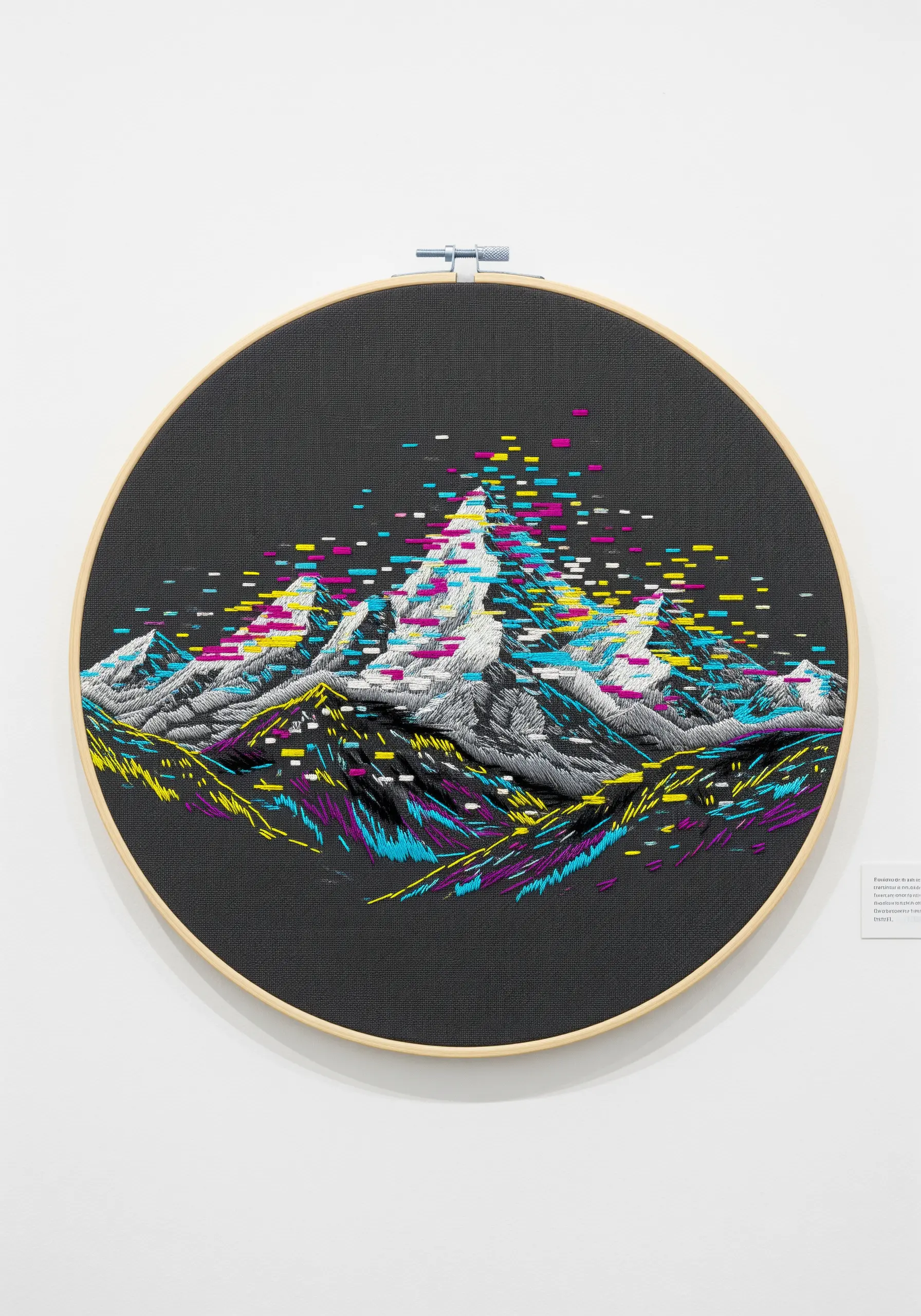 Embroidered mountain landscape with a vibrant, pixelated glitch effect stitched over it.