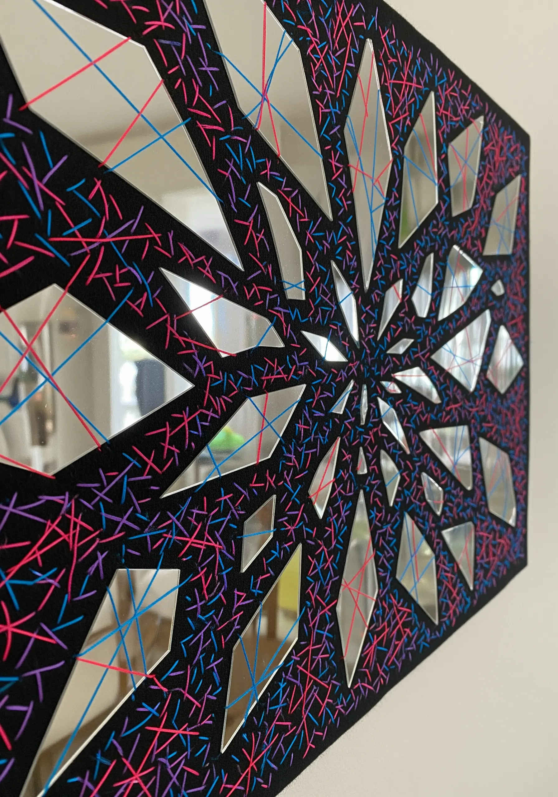 Abstract mosaic of thread and mirror shards on a black background.