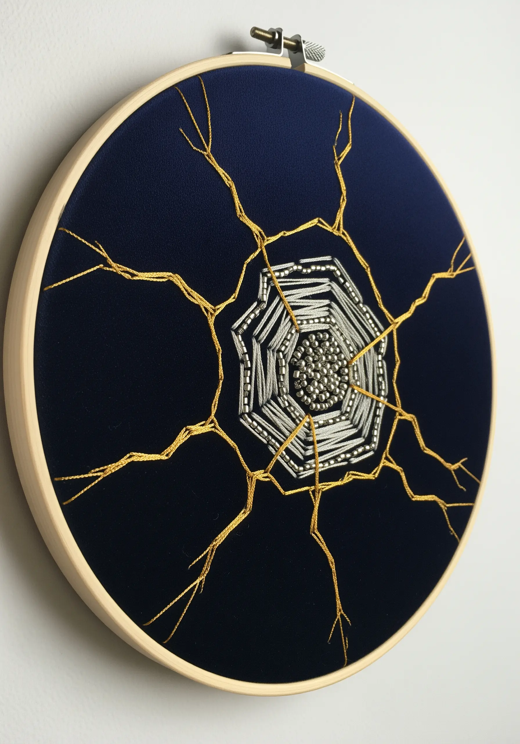 Kintsugi-style gold and silver metallic thread embroidery on dark navy fabric.