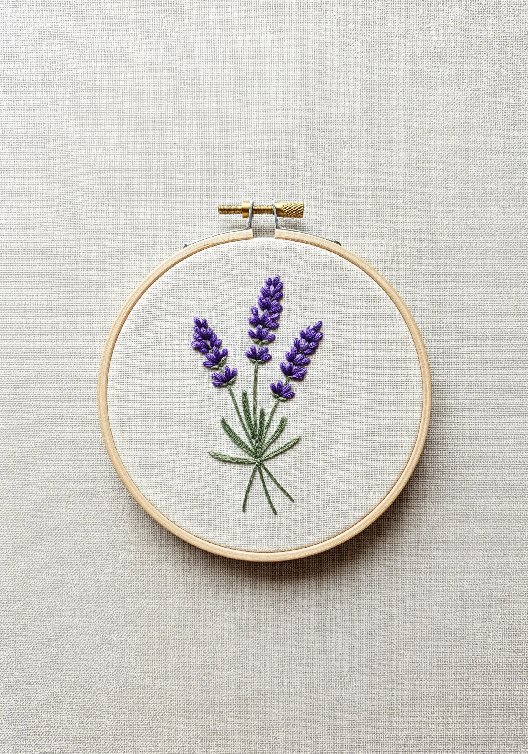 Embroidered lavender sprigs with purple French knots and green stems in a wooden hoop.