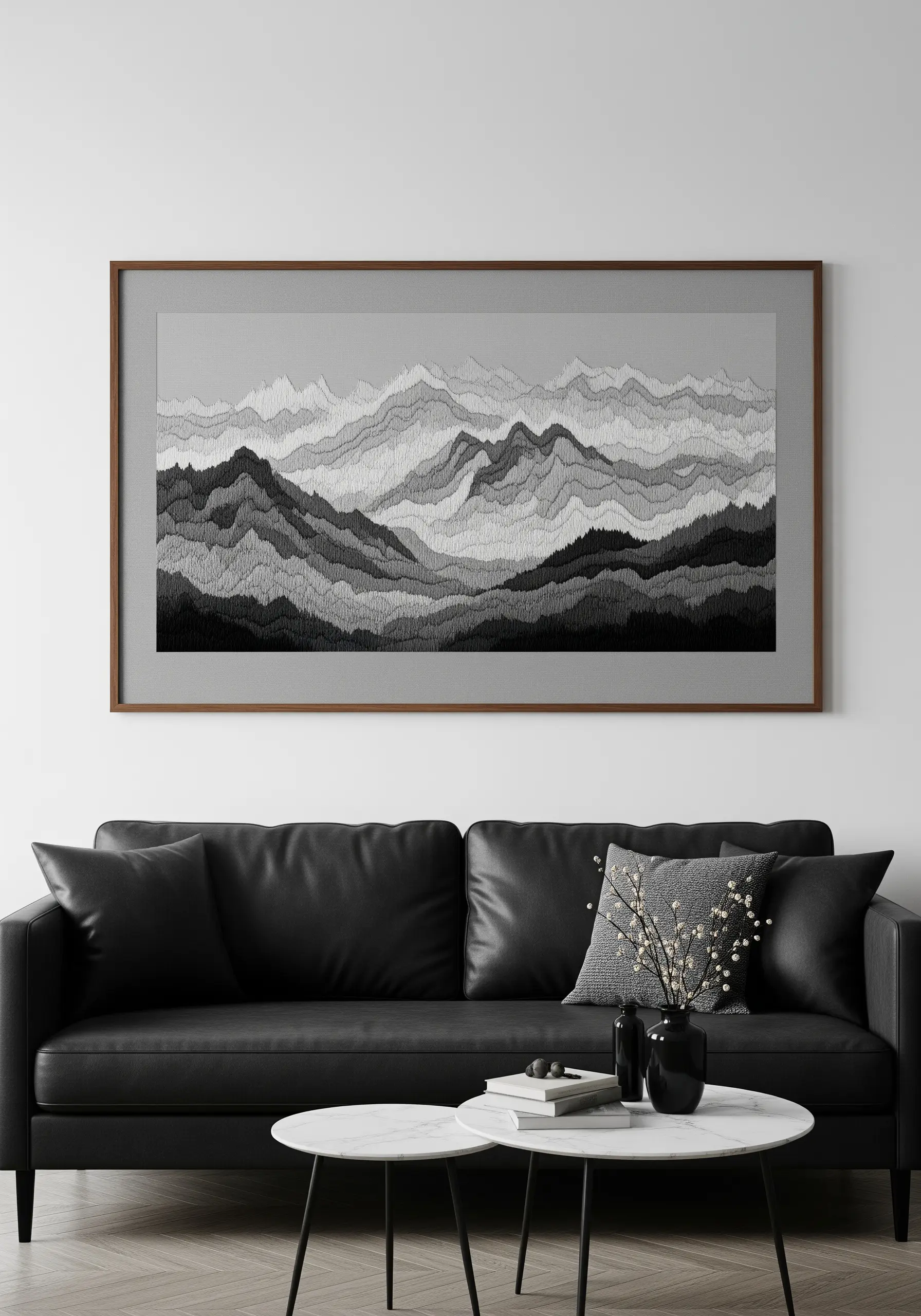 A framed panoramic embroidery of a mountain range in monochrome shades of grey.
