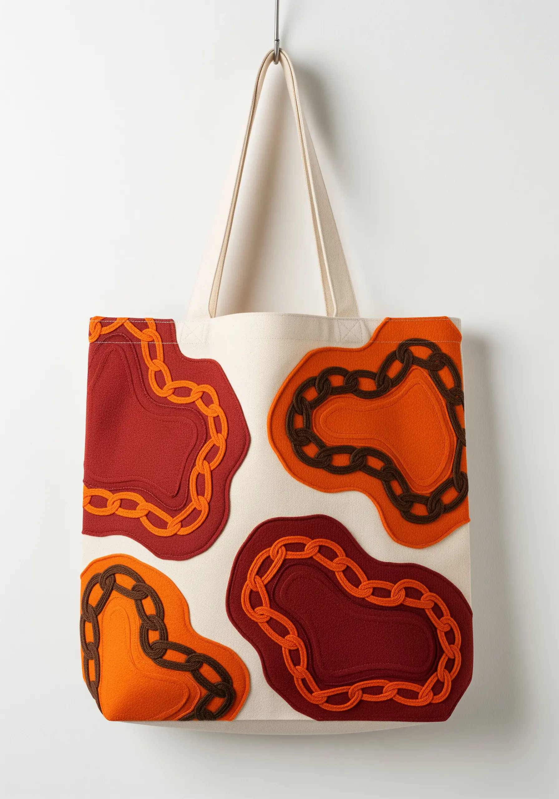 Tote bag with layered appliqué shapes in red and orange, outlined with brown chain stitch.