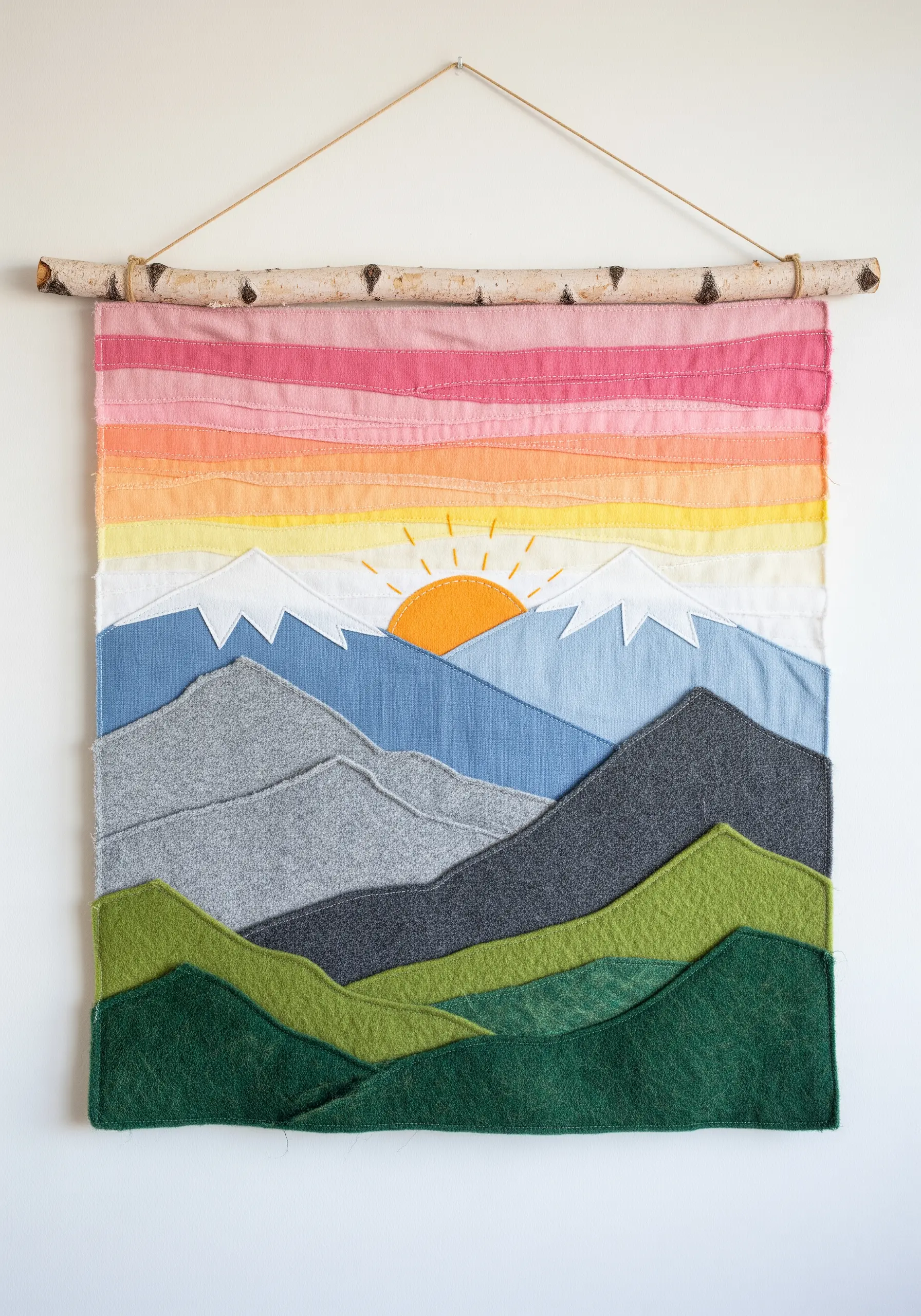 A mountain landscape wall hanging made from layers of different colored and textured fabrics