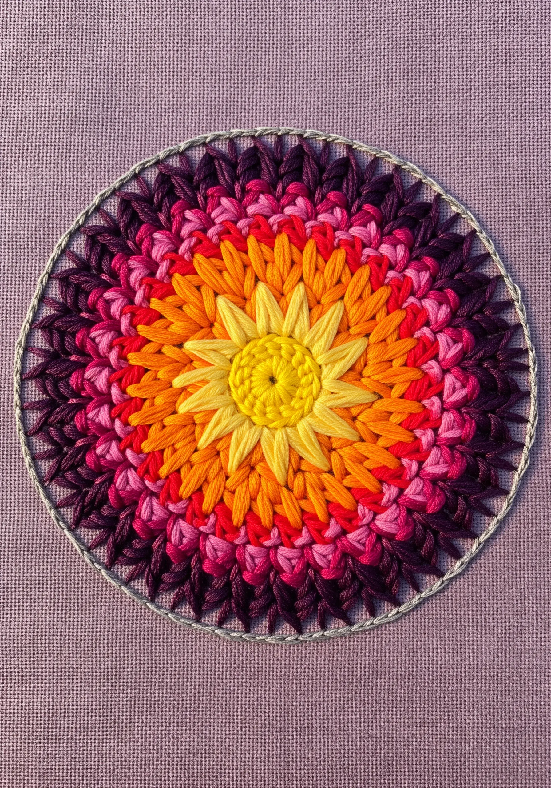A dense, colorful floral mandala with layered petals in a sunset-inspired color gradient.