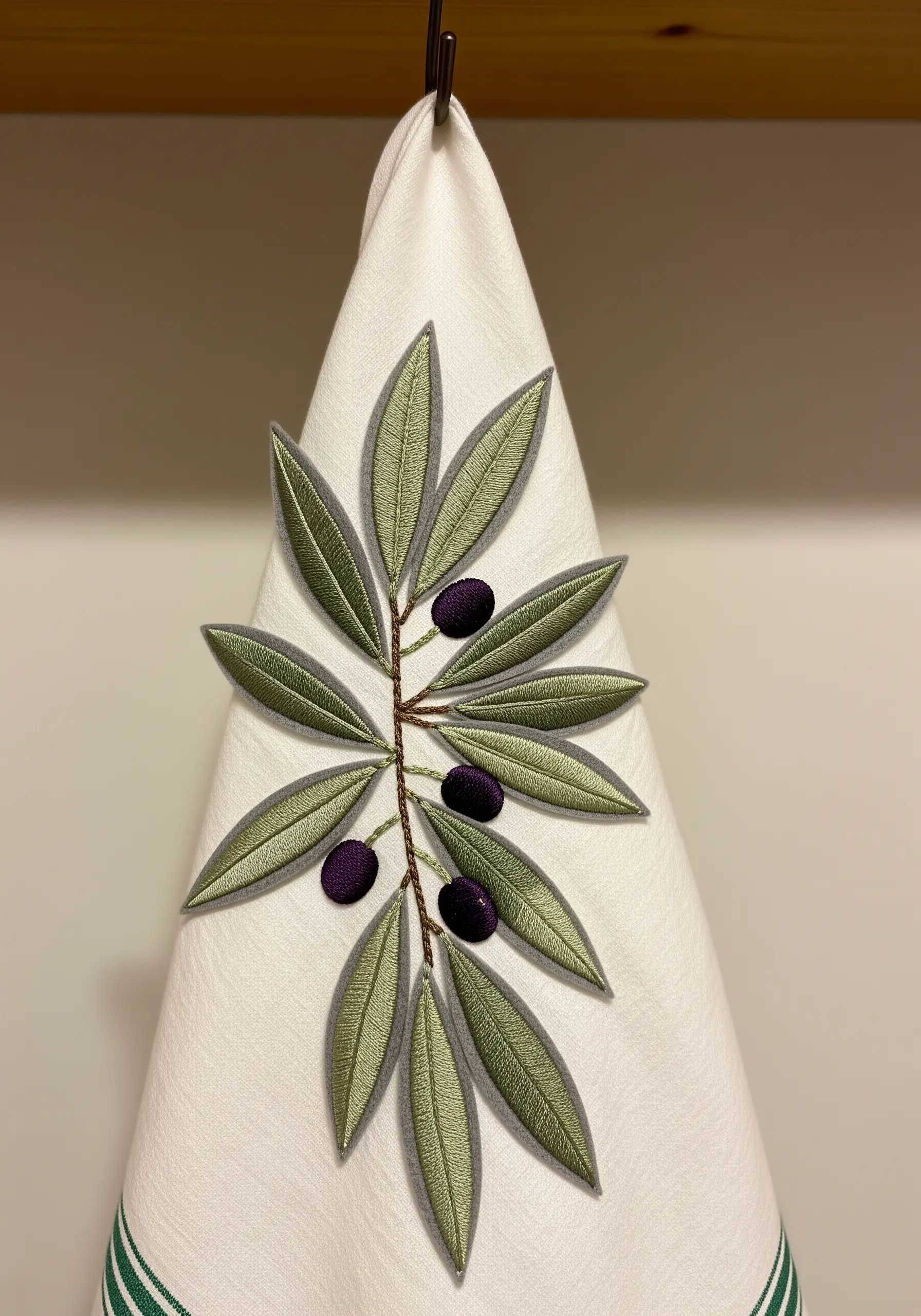 An olive branch with two-tone green layered satin stitch leaves and purple French knot olives.