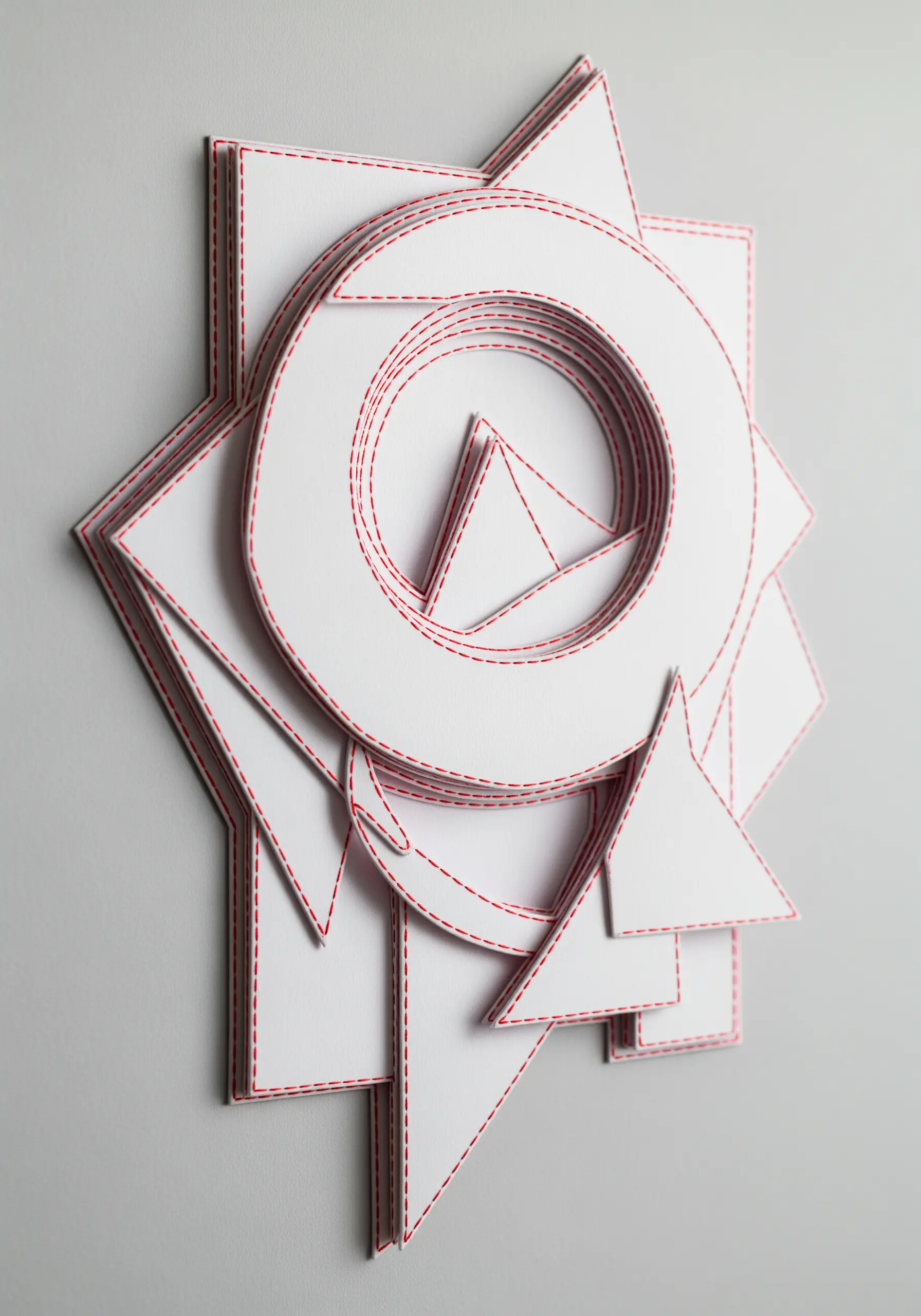 Layered white paper geometric shapes, each outlined with a simple red running stitch.