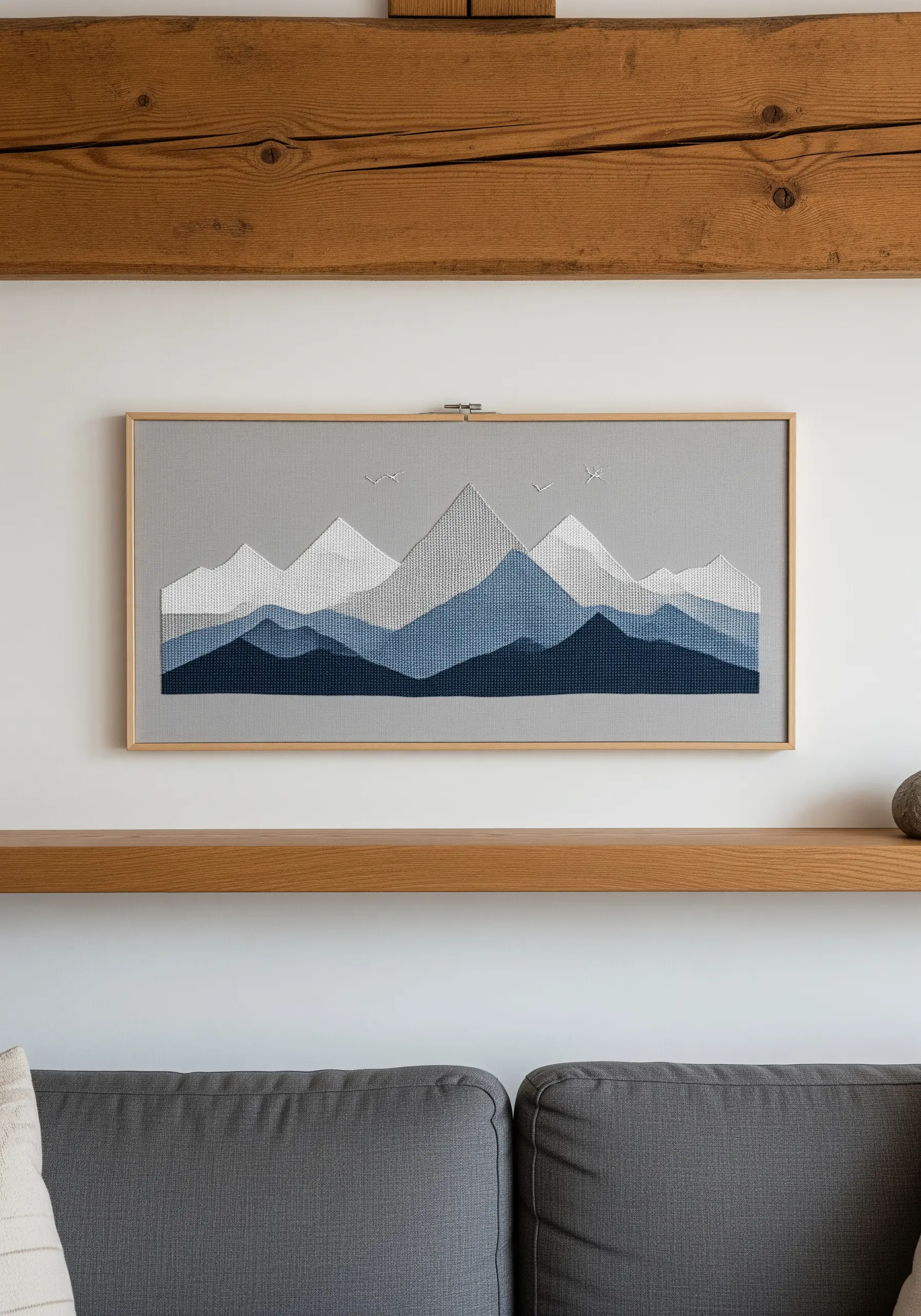 Embroidered mountain landscape with layered blue tones in a rectangular frame.