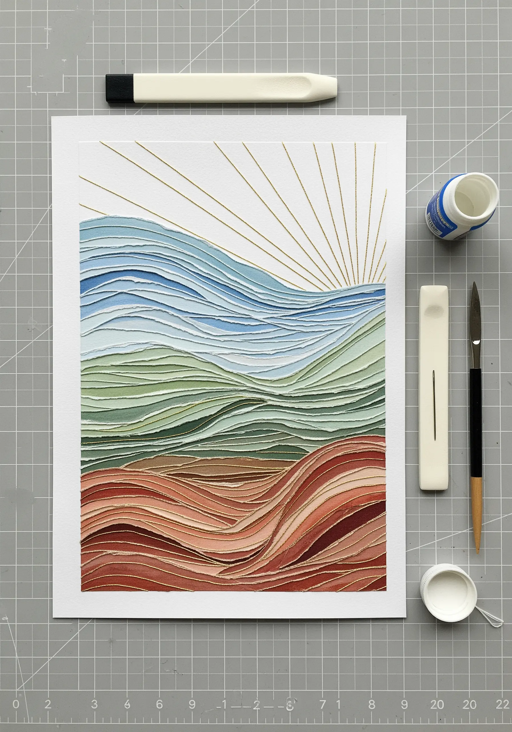 A layered paper collage of a landscape with stitched golden sun rays.