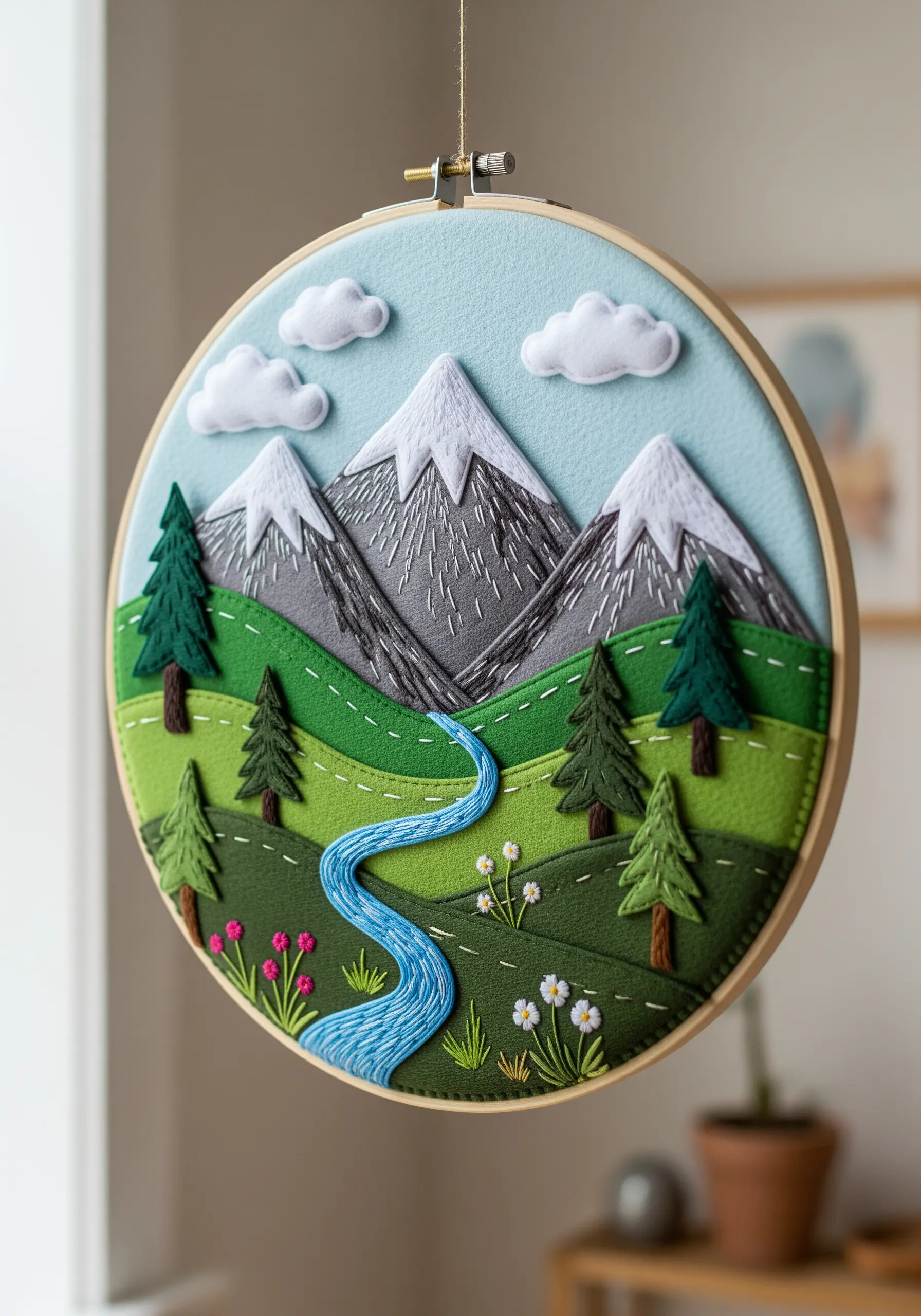 A dimensional landscape scene in an embroidery hoop, created with layered felt and thread details.