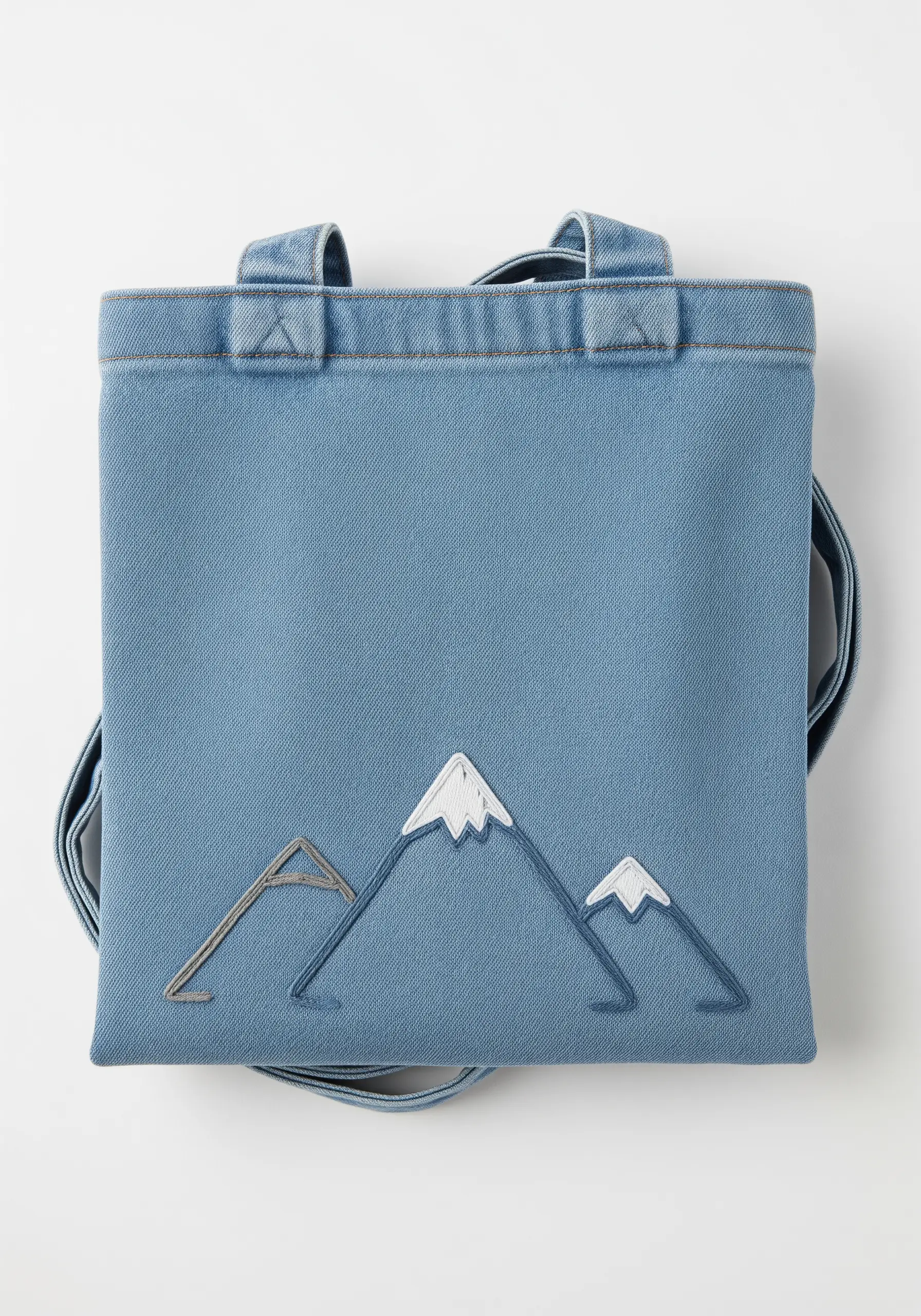 Stylized mountain range on a denim bag with layered outlines and satin stitch peaks.