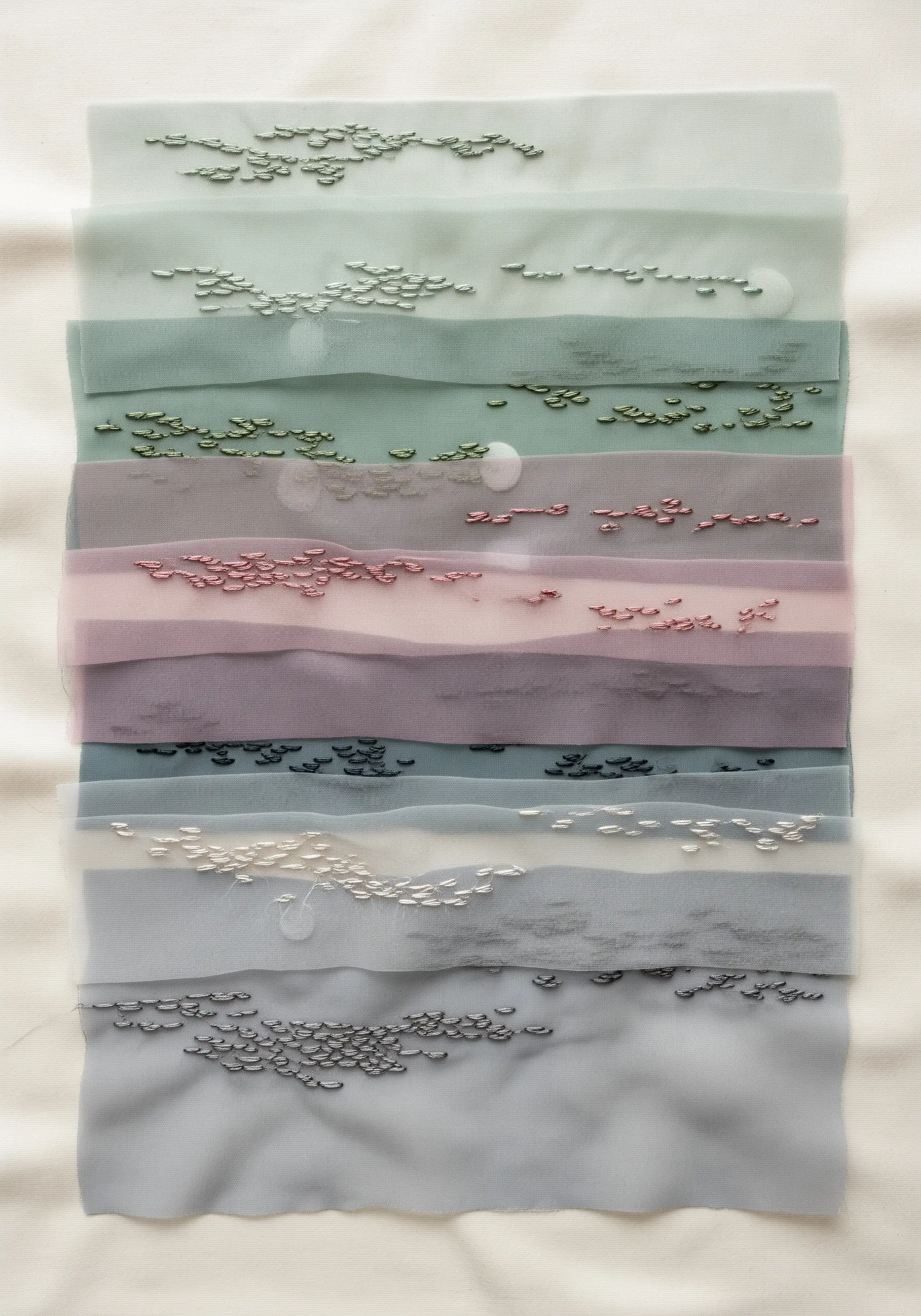 Layered sheer fabrics in muted tones with scattered seed stitches creating a sense of depth.