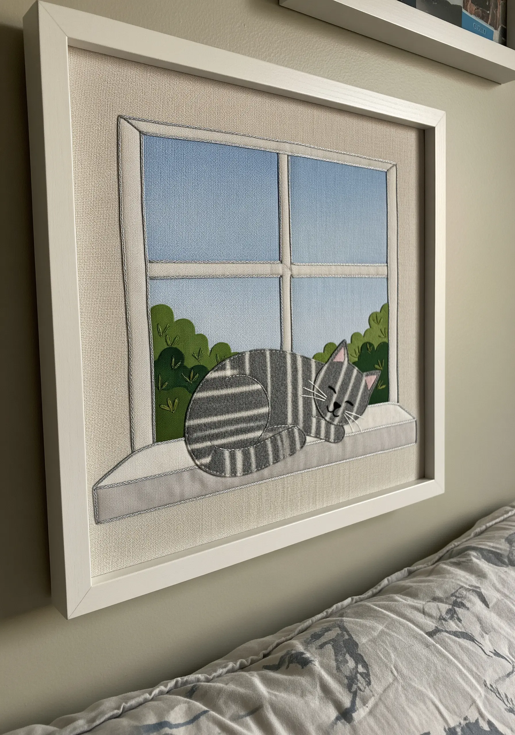 Framed fabric collage of a sleeping cat made from striped gray fabric