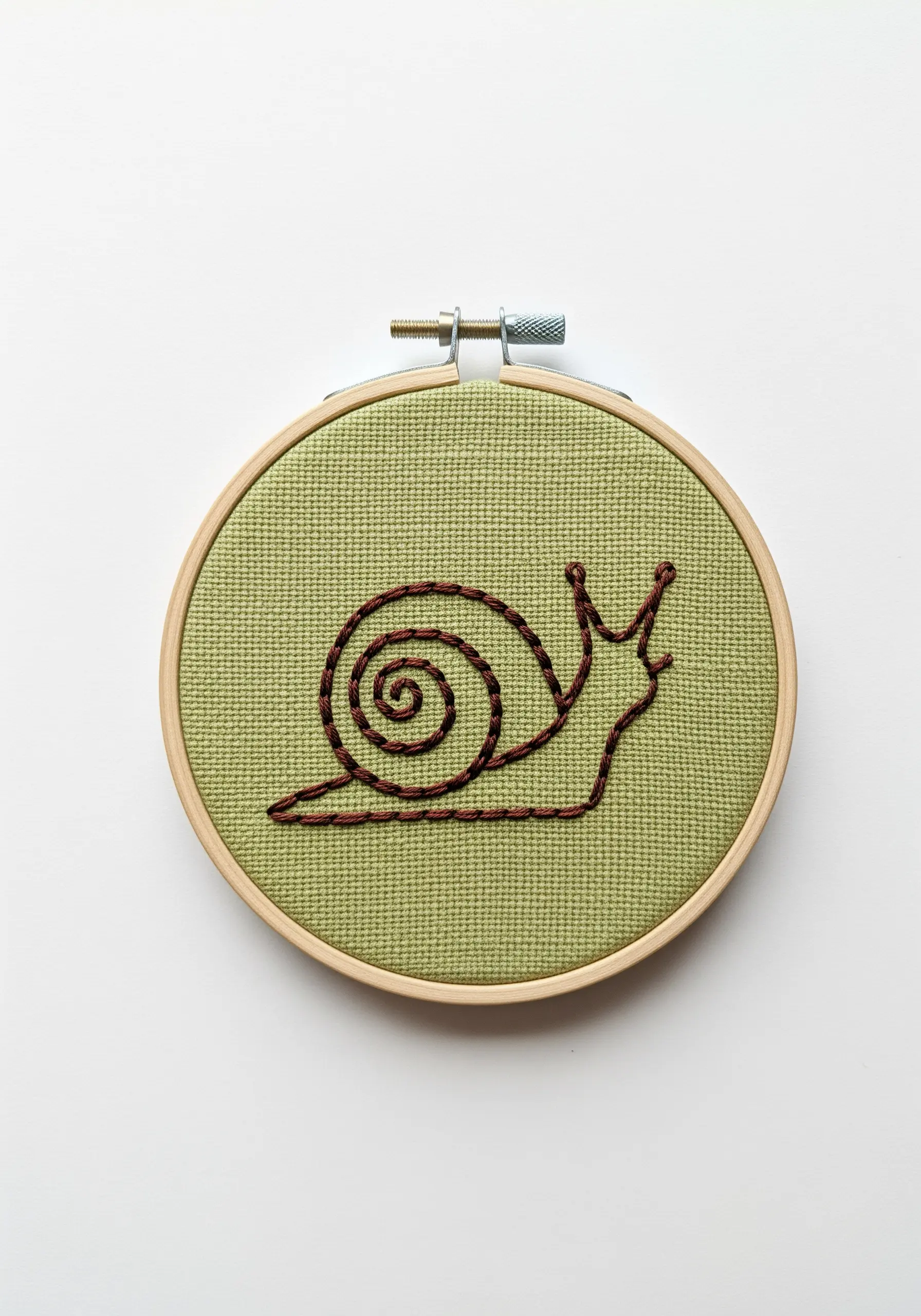 A simple outline of a snail stitched on green Aida cloth with variegated brown thread.