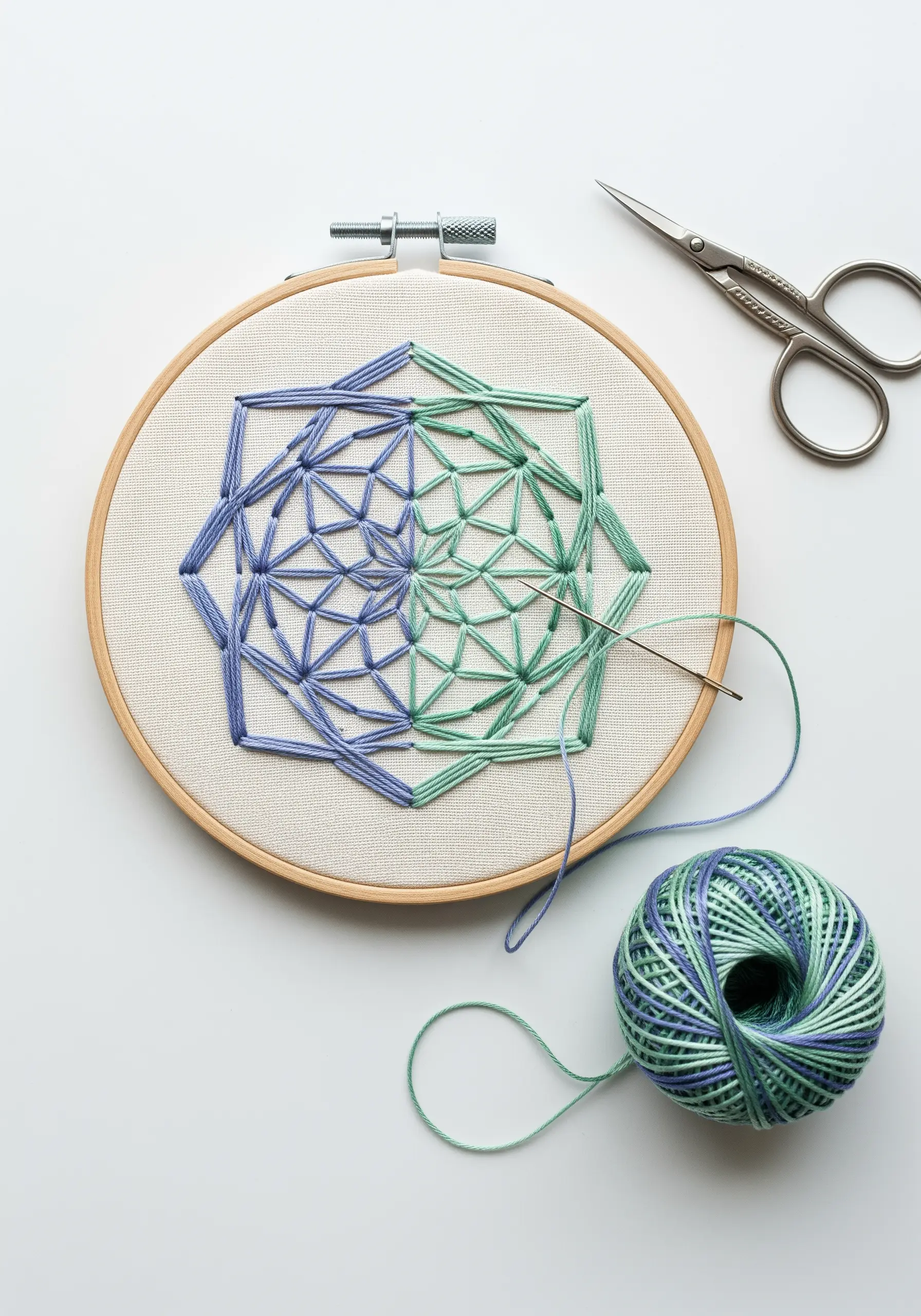 A geometric mandala stitched with blue and green variegated thread, showing color transitions.