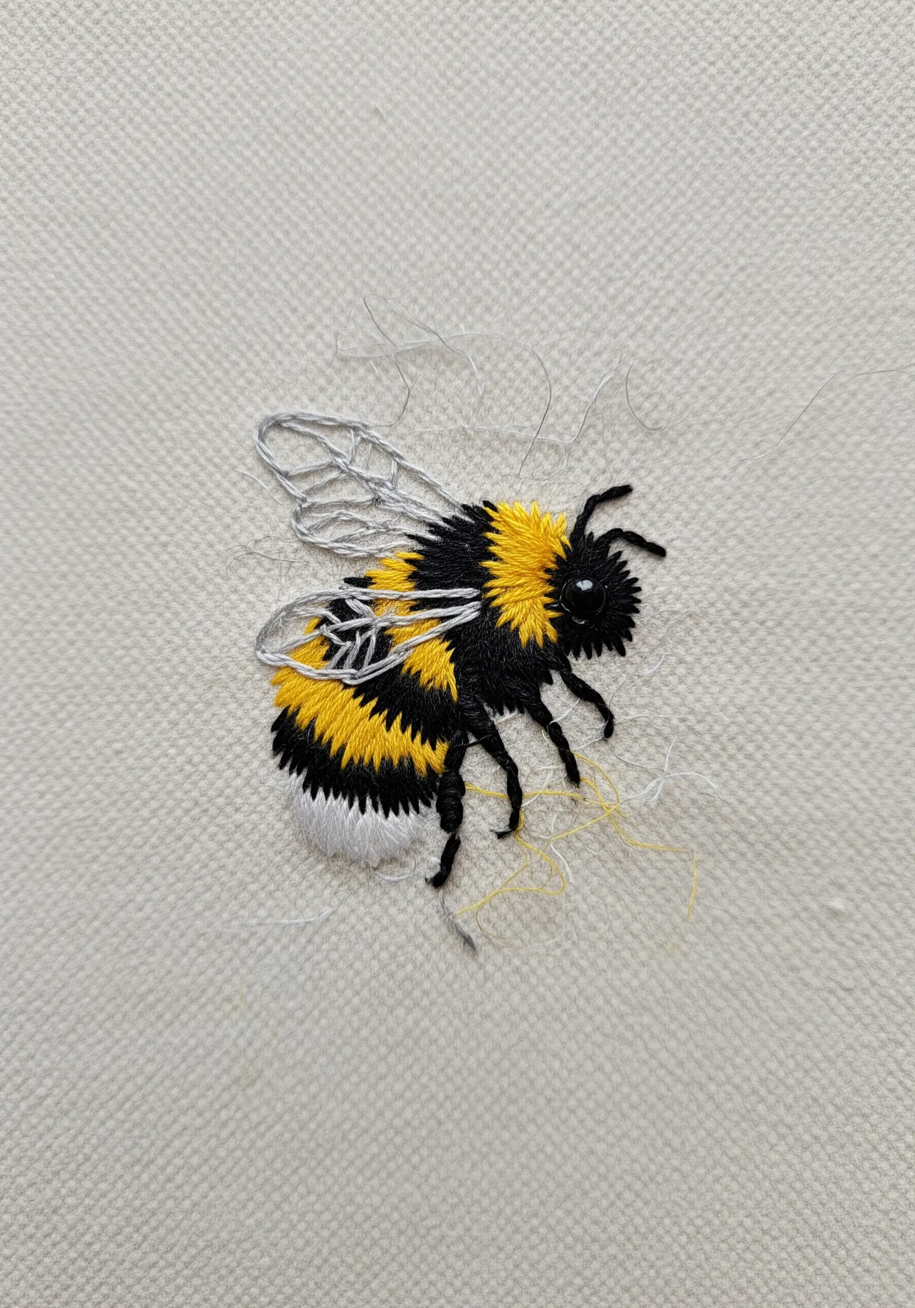 Detailed thread-painted bumblebee with fuzzy yellow and black stripes and delicate wings.