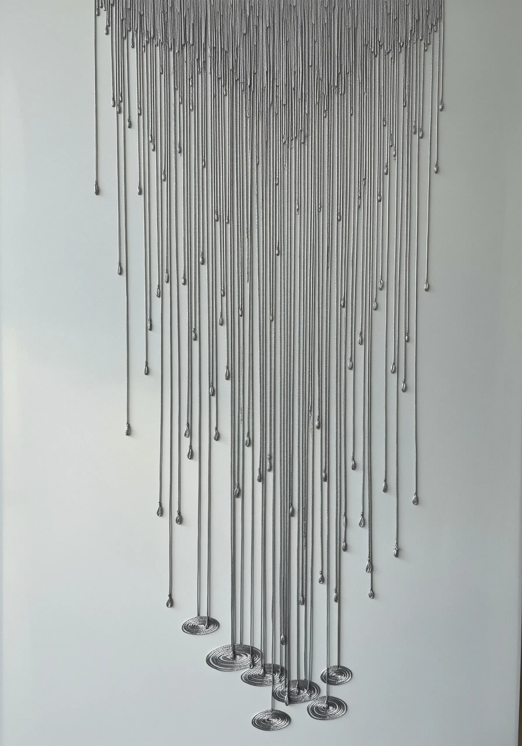 Sculptural embroidery with silver threads that look like dripping liquid metal on a white canvas.