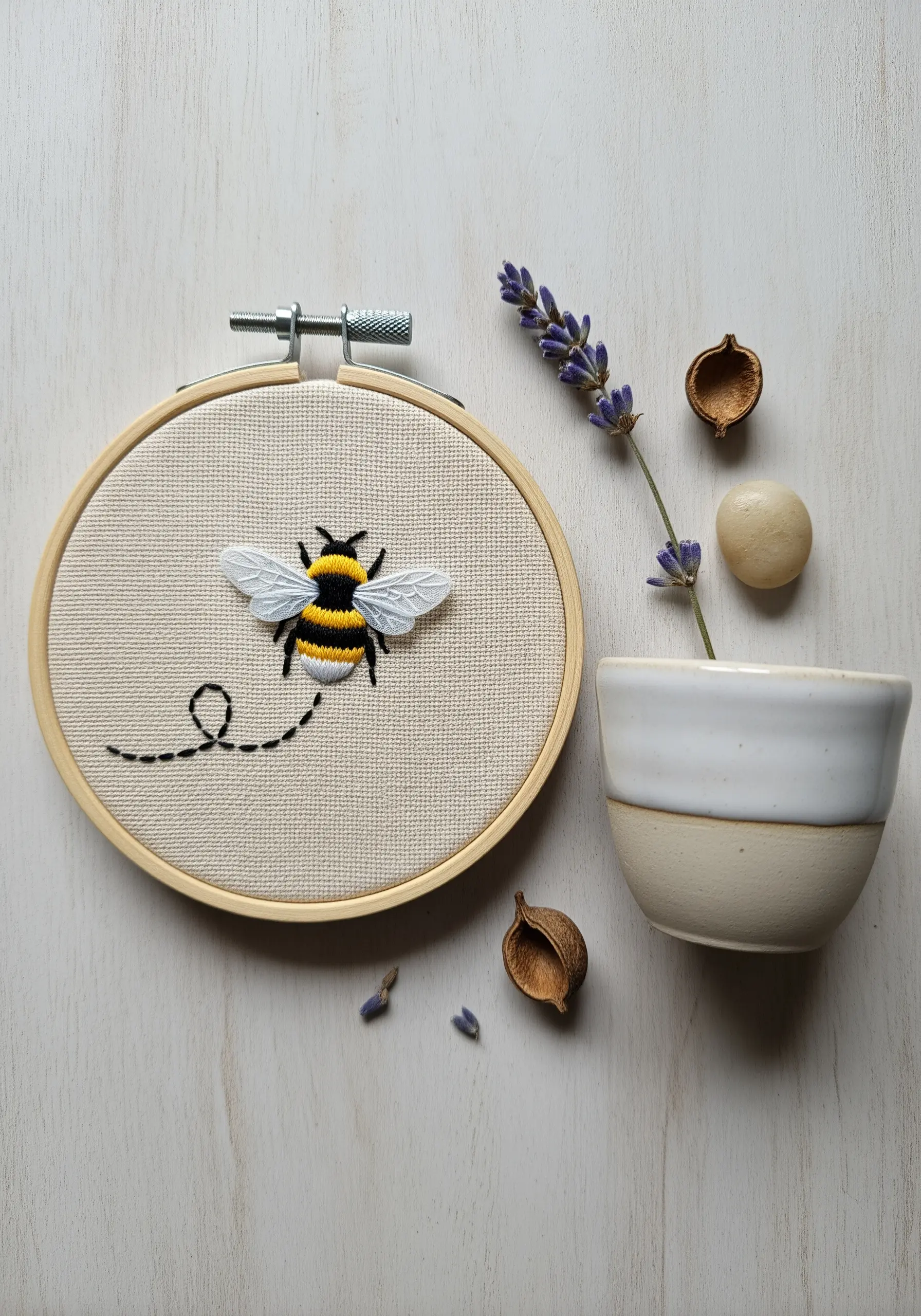 Embroidered bumblebee with satin stitch body and delicate single-thread wings.