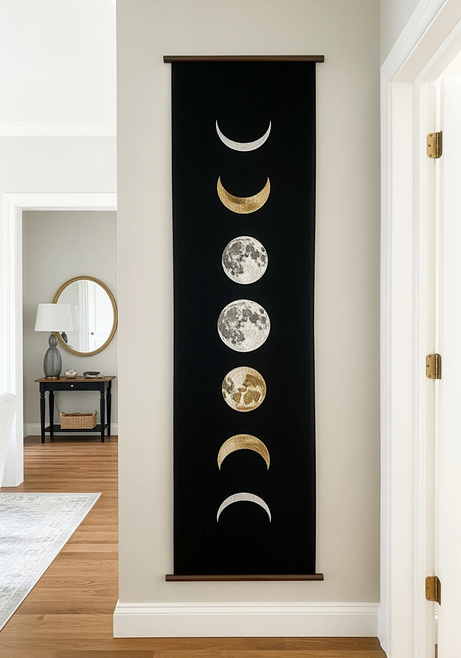 A tall black wall hanging embroidered with the phases of the moon in silver, white, and gold.