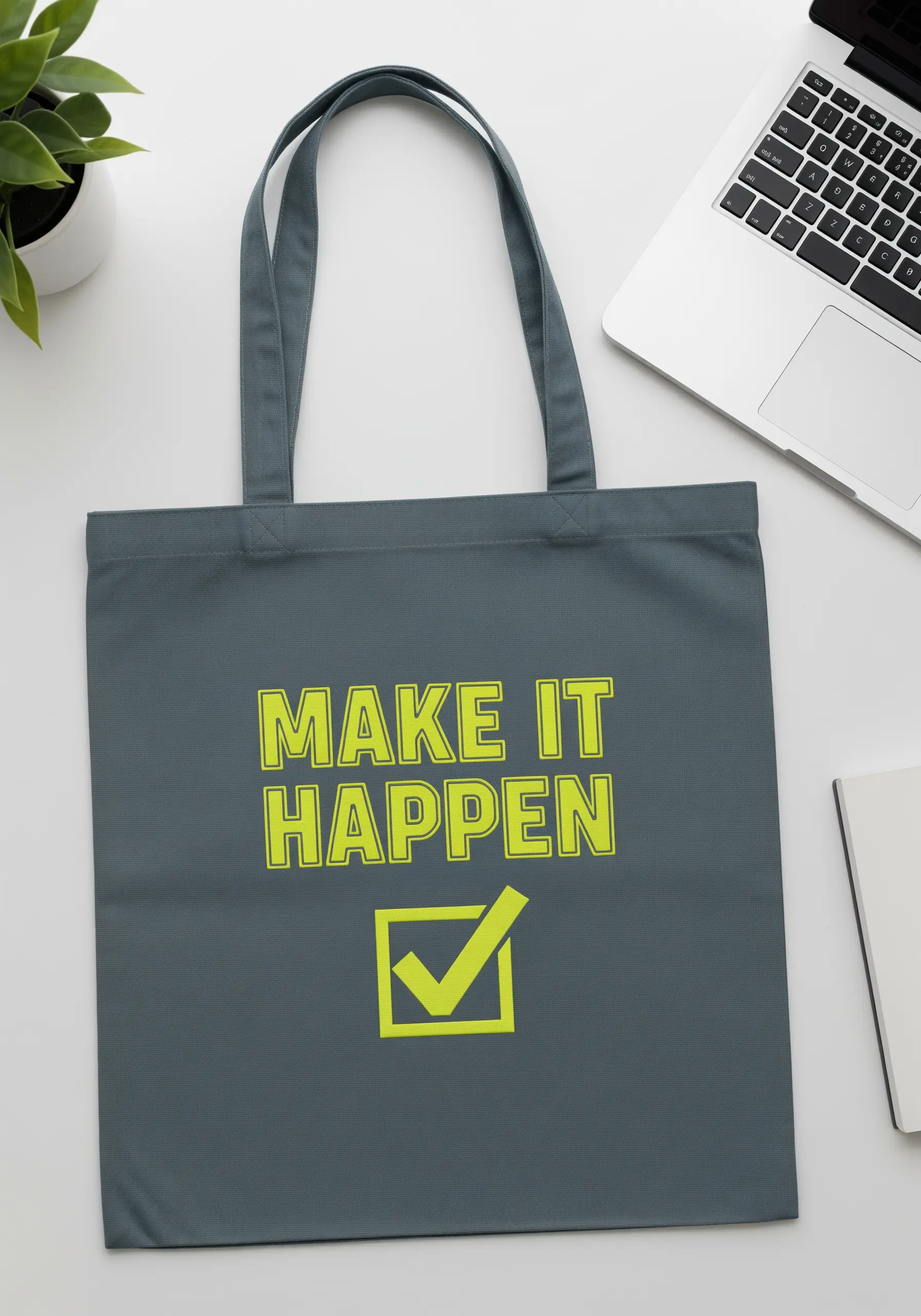 Bold, neon yellow embroidered text 'Make It Happen' with a checkmark on a dark grey tote bag.